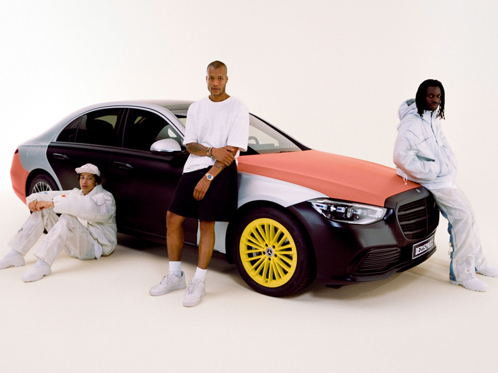 De afbeelding toont 3 mannen naast een mercedes-benz