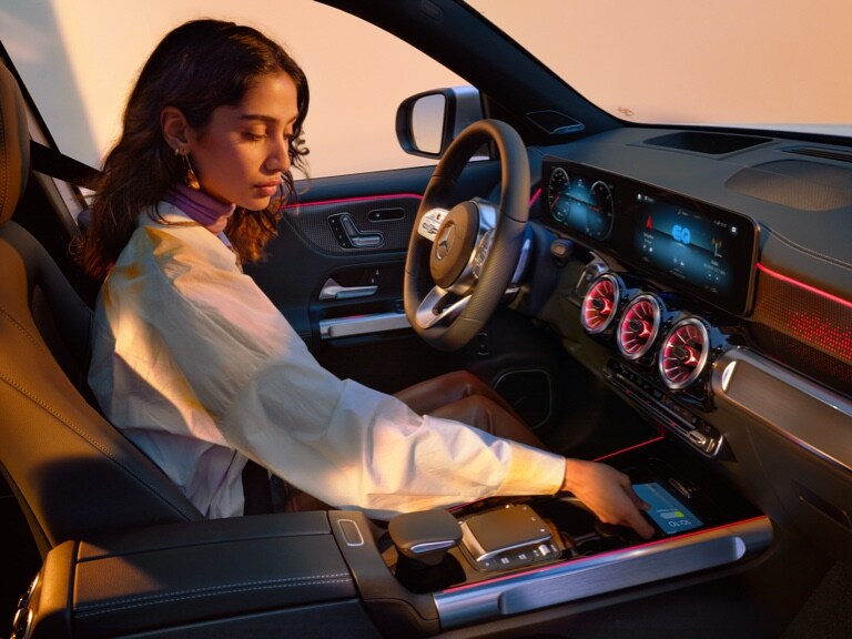 Een vrouw laadt haar smartphone draadloos op het oplaadvlak van haar Mercedes-Benz op.