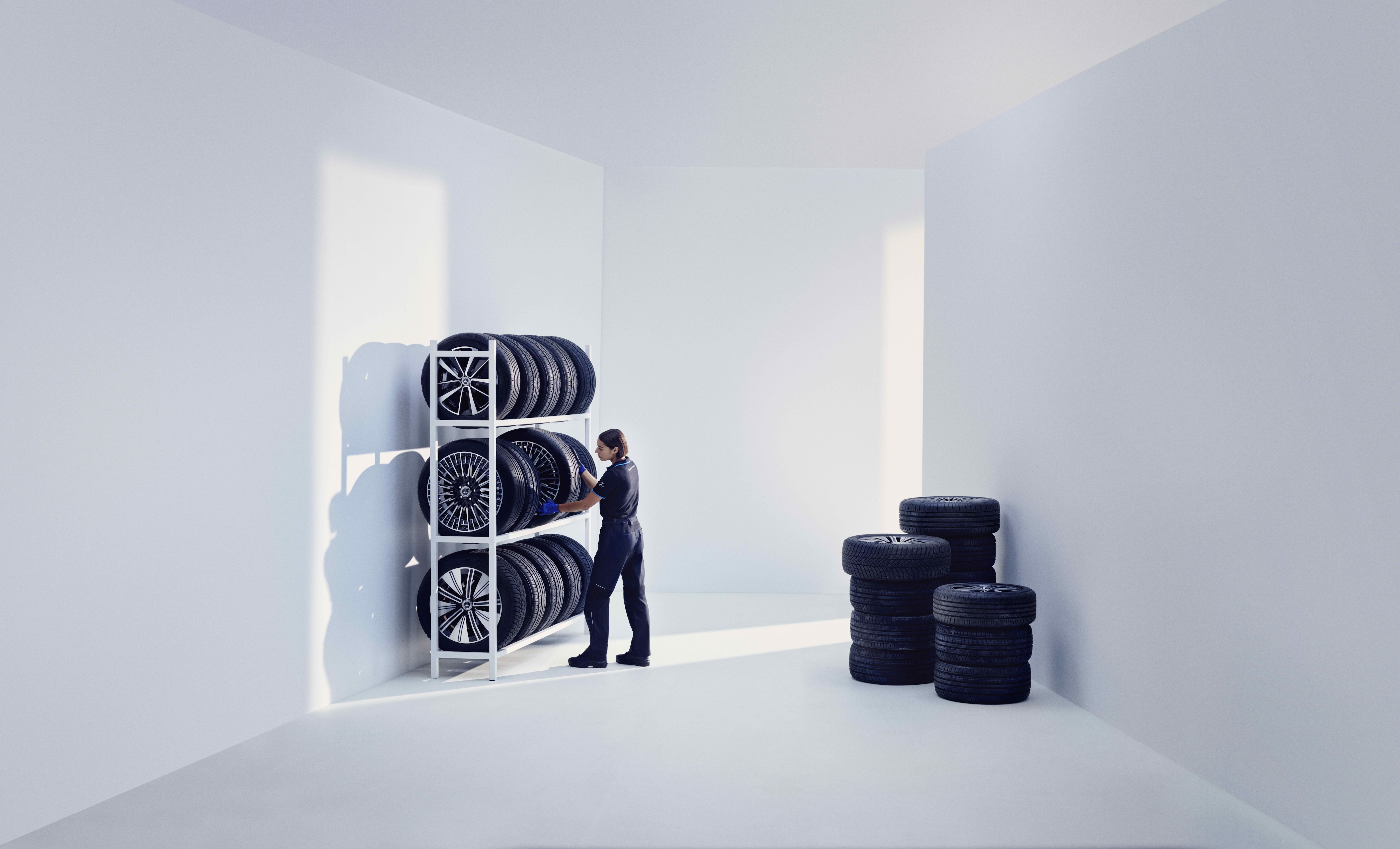 Originele banden | Mercedes-Benz Een Mercedes-Benz technicus slaat originele Mercedes-Benz banden op een stellage op.