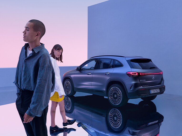 Twee personen staan vóór een Mercedes-Benz personenwagen