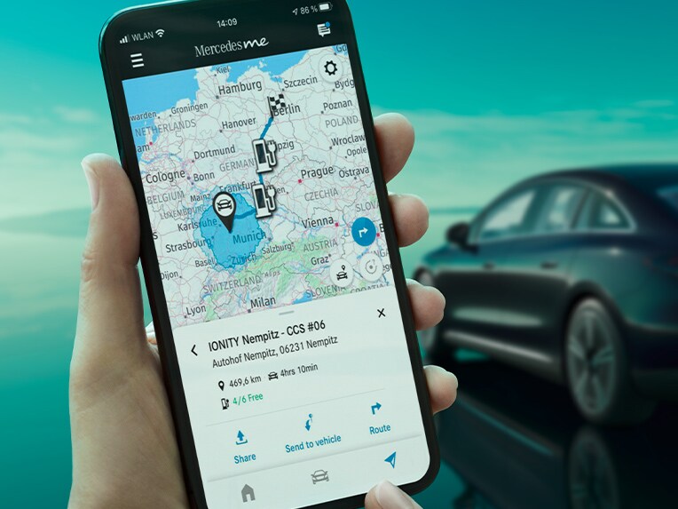 De Eco Coach-app op een smartphone en op de achtergrond de EQE Limousine tijdens het opladen vanuit een wallbox.