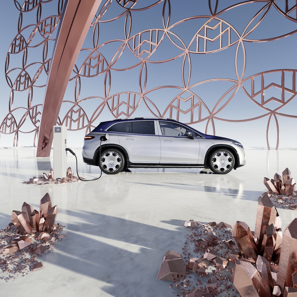 Zijaanzicht van de Mercedes-Maybach EQS SUV bij het laadstation, met het Maybach merklogo op de achtergrond.