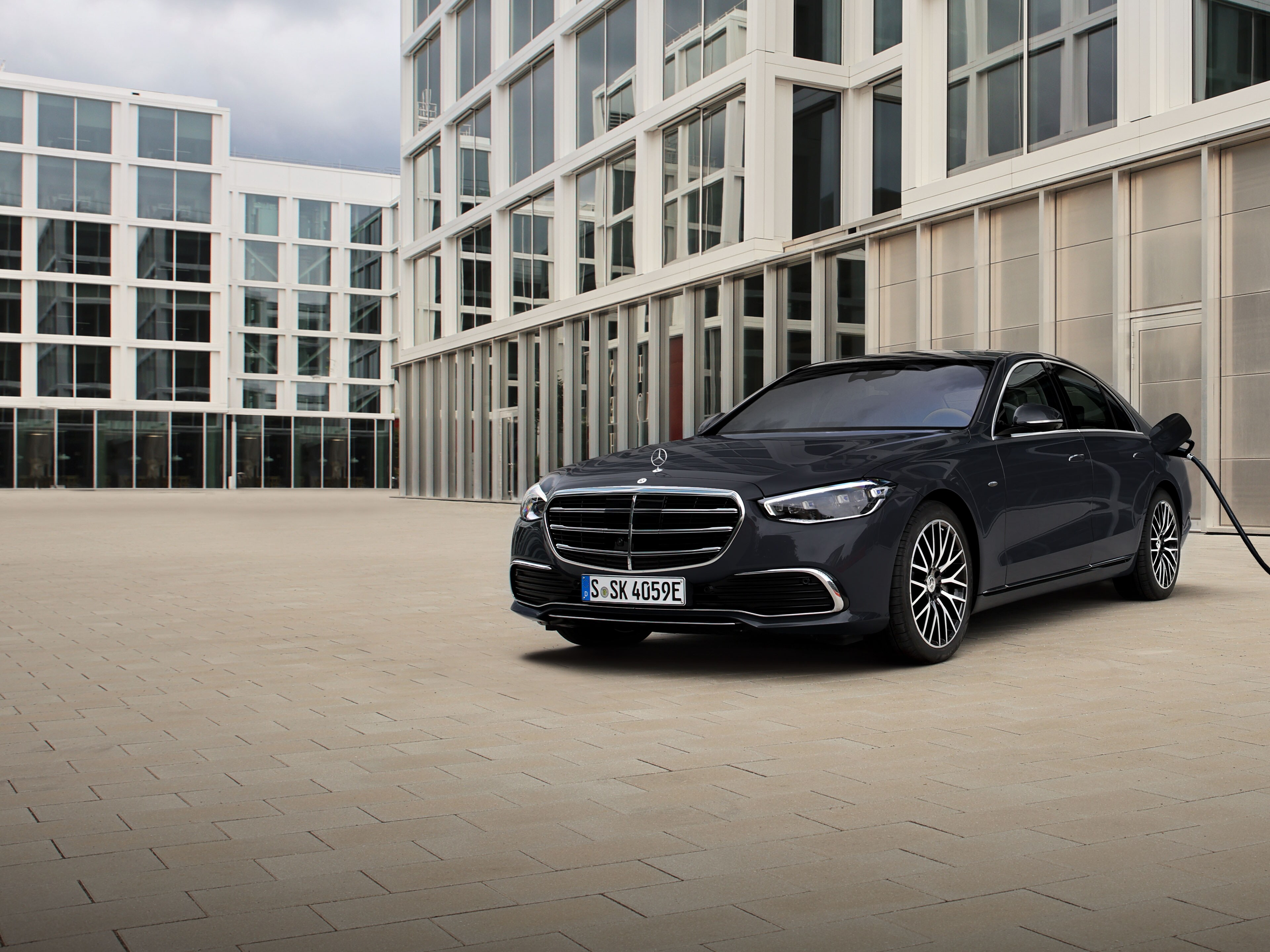 Het beeld toont een Mercedes-Benz E-Klasse op een parking met op de achtergrond gebouwen.