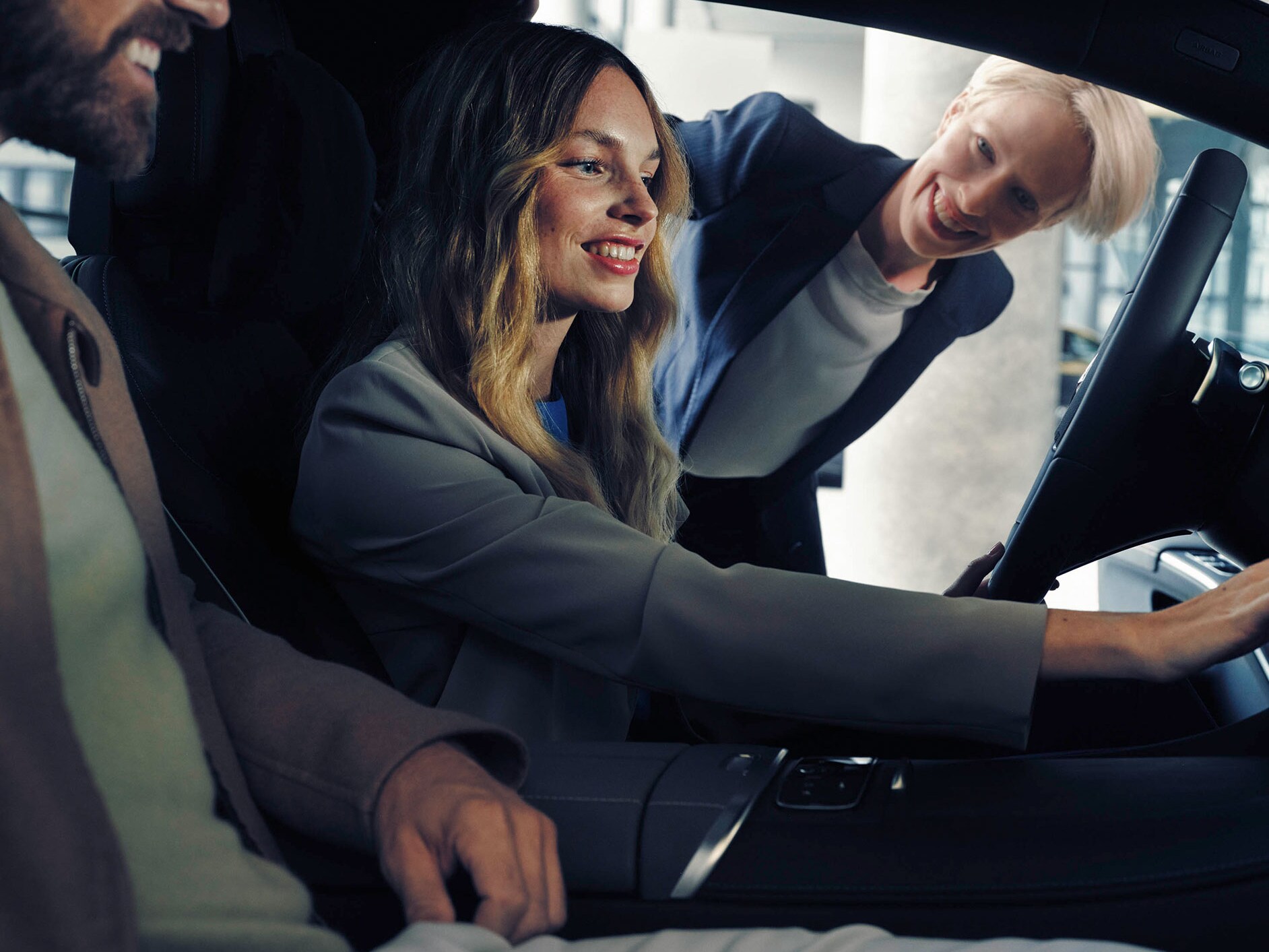 Man and woman sat in Mercedes-Benz EQS with a dealer looking at interior features