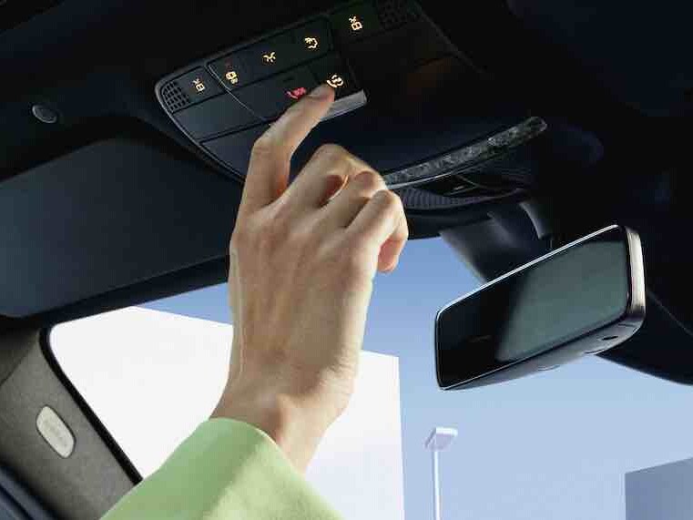 De Mercedes me-knop in het bedieningspaneel van de dakconsole van een Mercedes-Benz wordt ingedrukt.