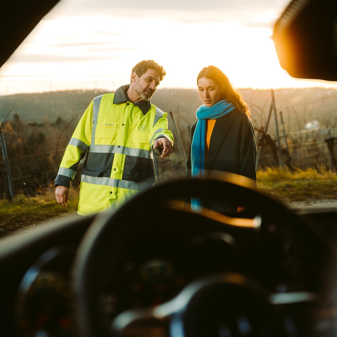 Door de voorruit van een Mercedes-Benz zien we een servicemonteur die naast de bestuurder voor de auto staat en naar de voorruit wijst.