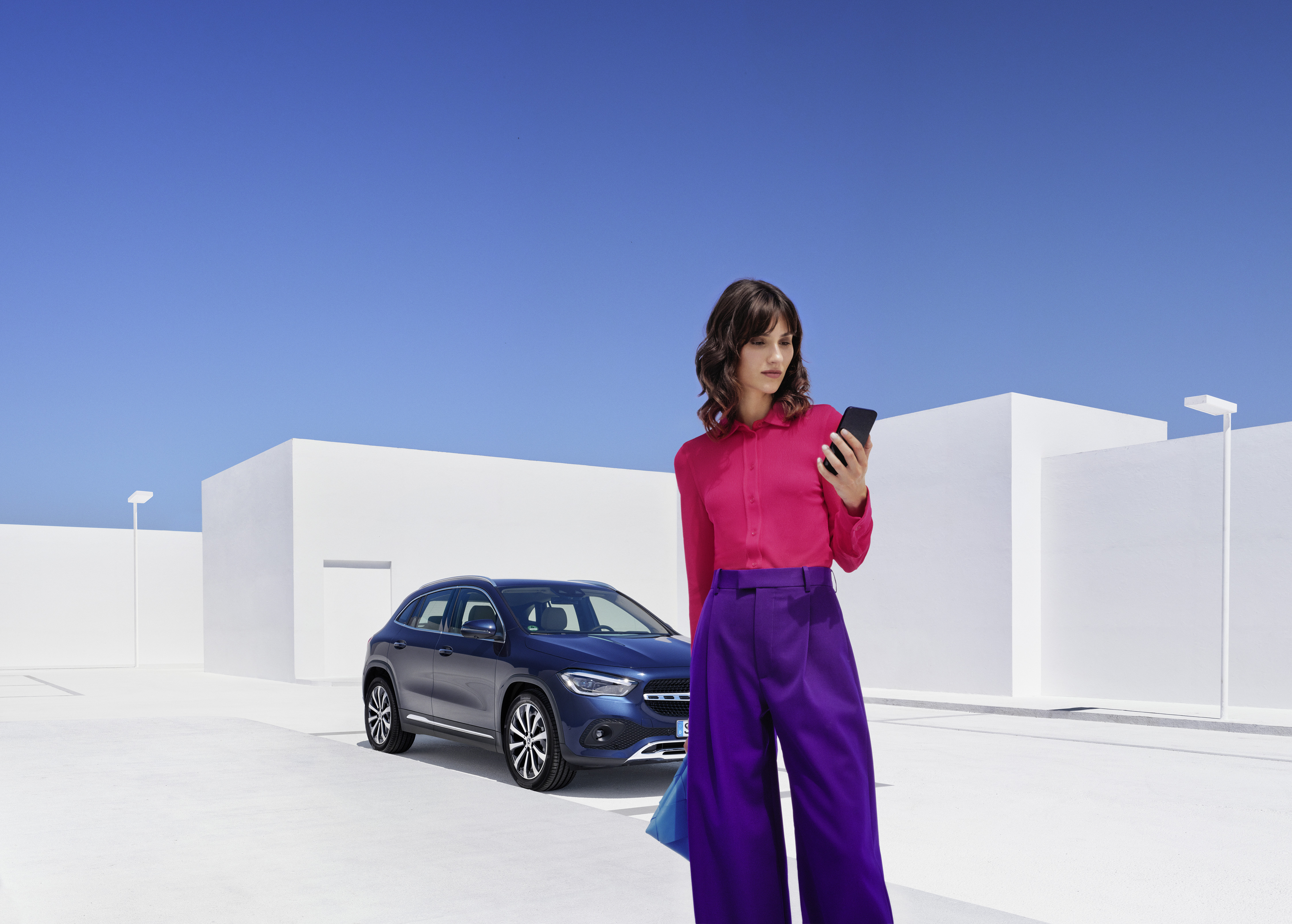 Hulp bij pech | Mercedes-Benz Een vrouw staat voor haar Mercedes-Benz en kijkt naar haar smartphone.