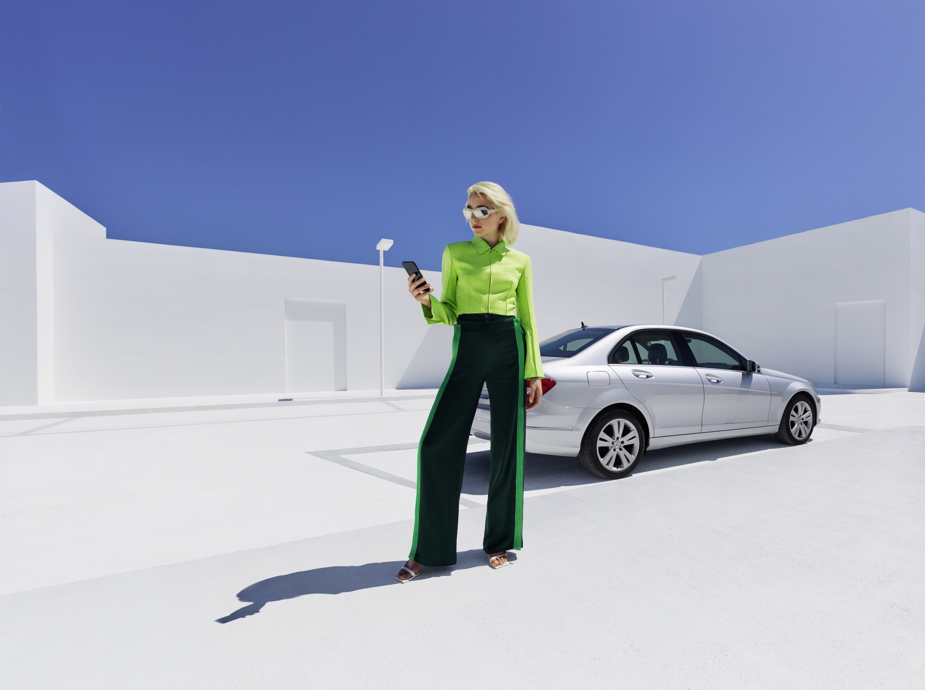 Mercedes-Benz Adapter Een vrouw staat voor haar Mercedes-Benz en kijkt naar haar smartphone.