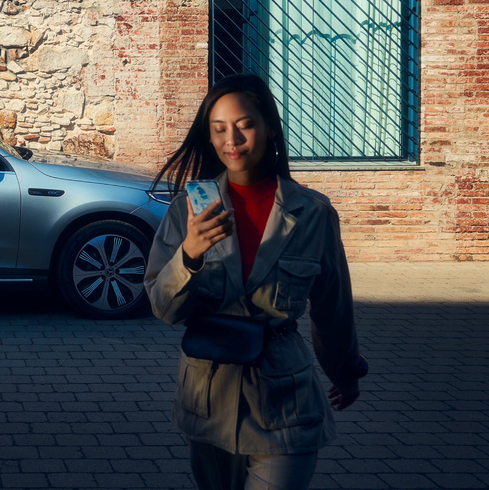 Een vrouw is met haar smartphone via digitale extra's met haar Mercedes-Benz verbonden.