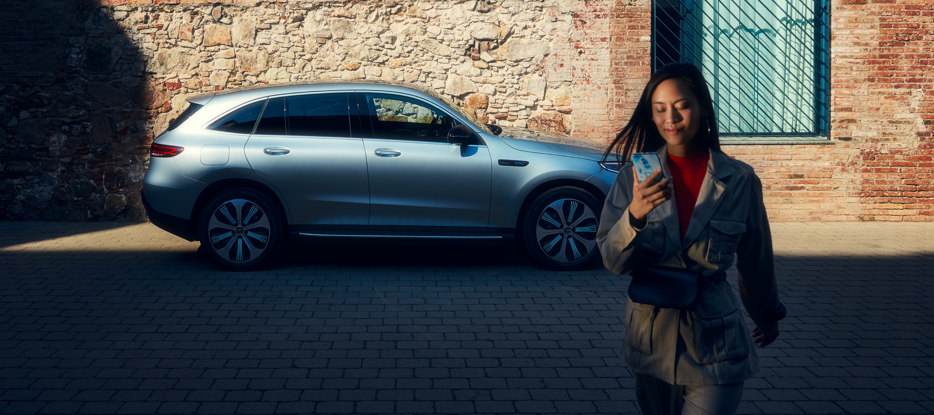 Een vrouw is met haar smartphone via digitale extra's met haar Mercedes-Benz verbonden. Een vrouw is met haar smartphone via digitale extra's met haar Mercedes-Benz verbonden.