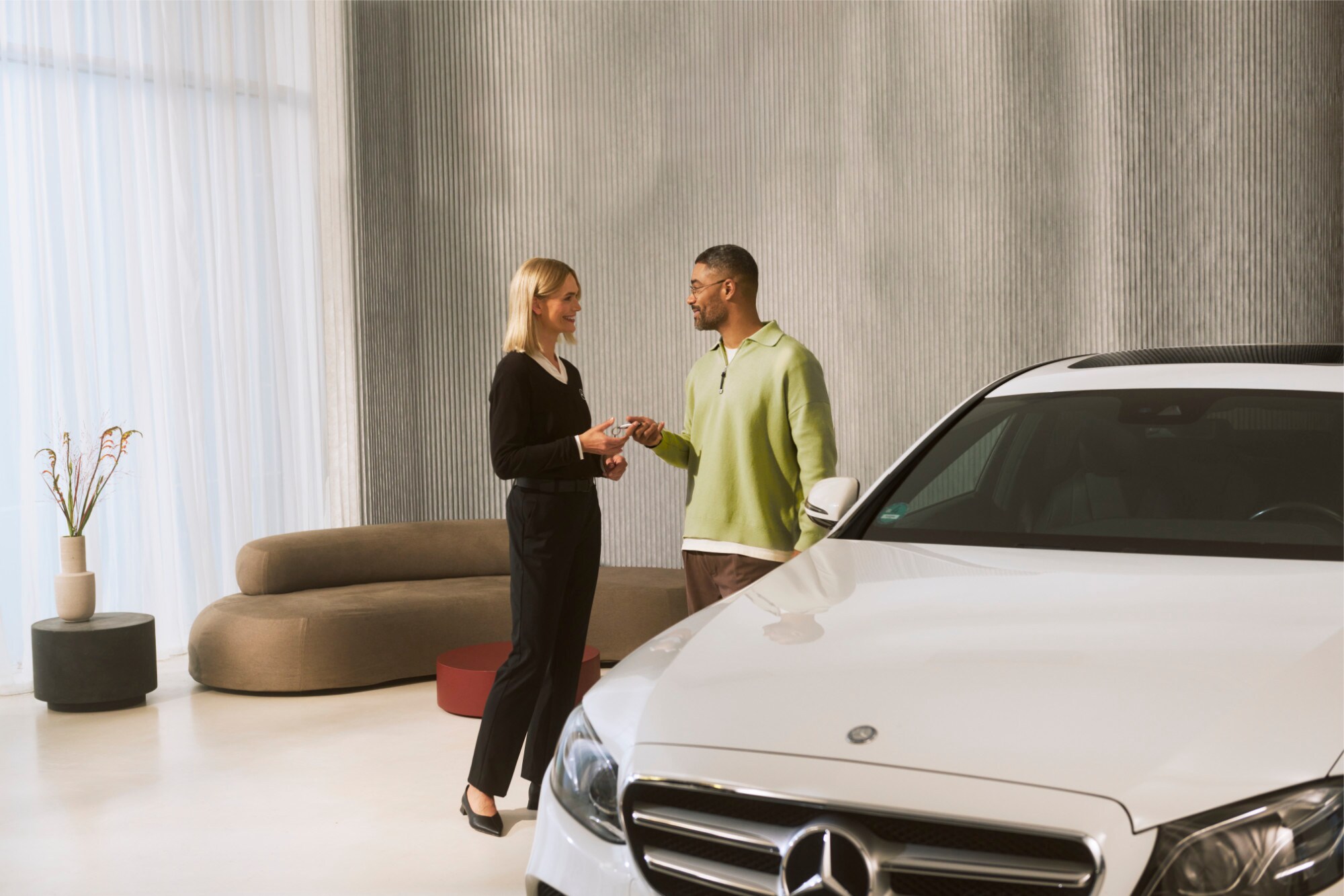 Een Mercedes-Benz adviseur overhandigt de autosleutels aan een klant.