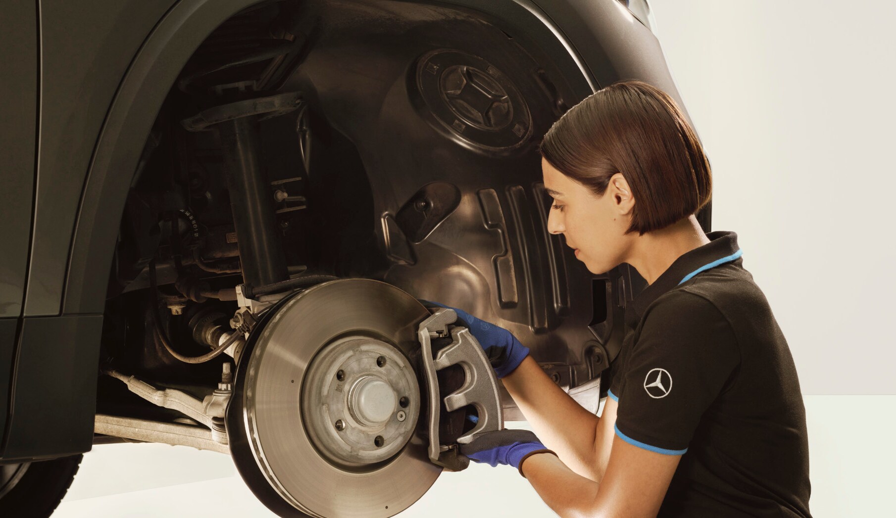 Een monteur repareert de remmen van een Mercedes-Benz voertuig.