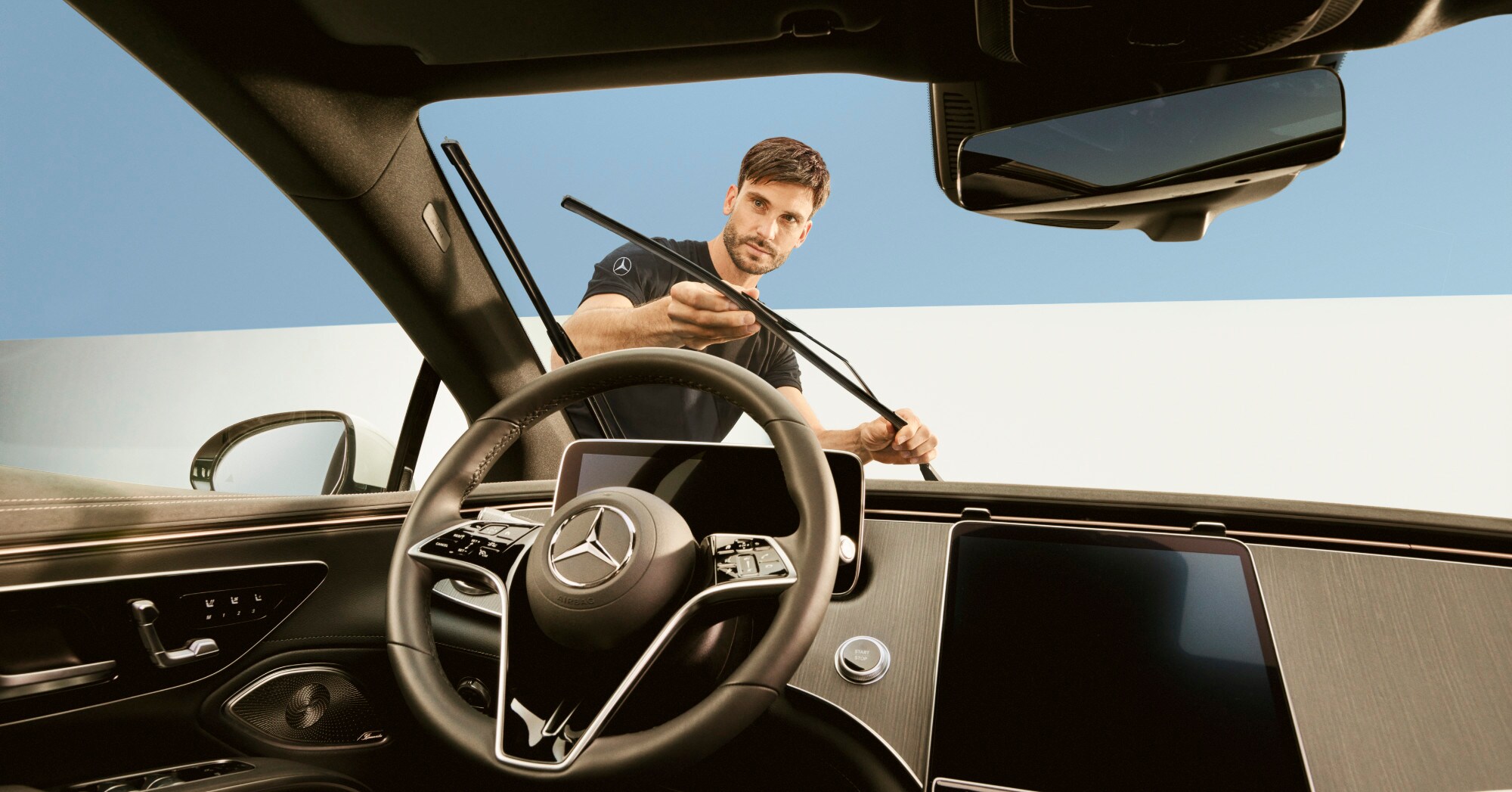 Een monteur repareert de ruitenwisserbladen van een Mercedes-Benz voertuig.