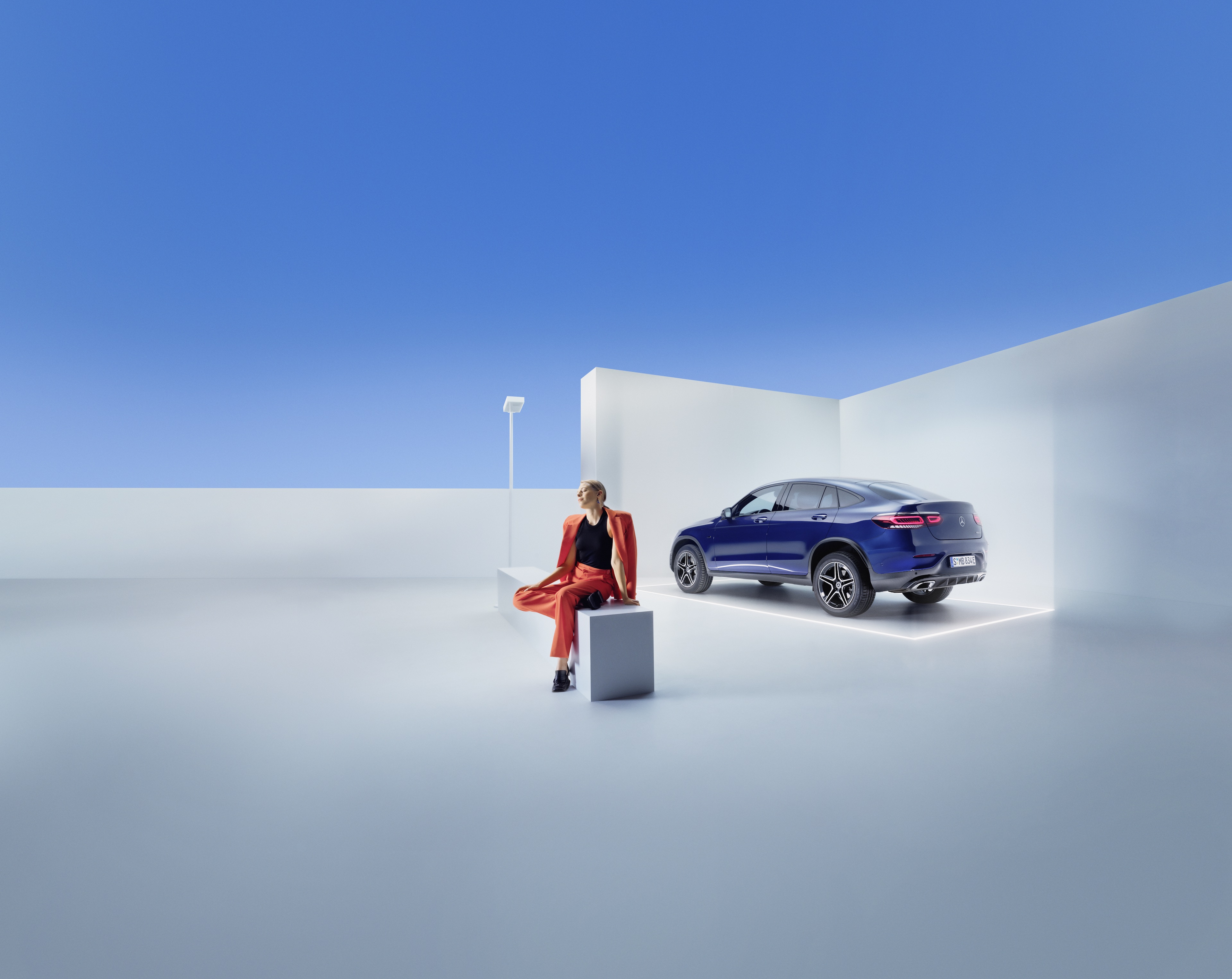 Mercedes-Benz servicecontracten Een vrouw zit op een bank vóór een Mercedes-Benz.