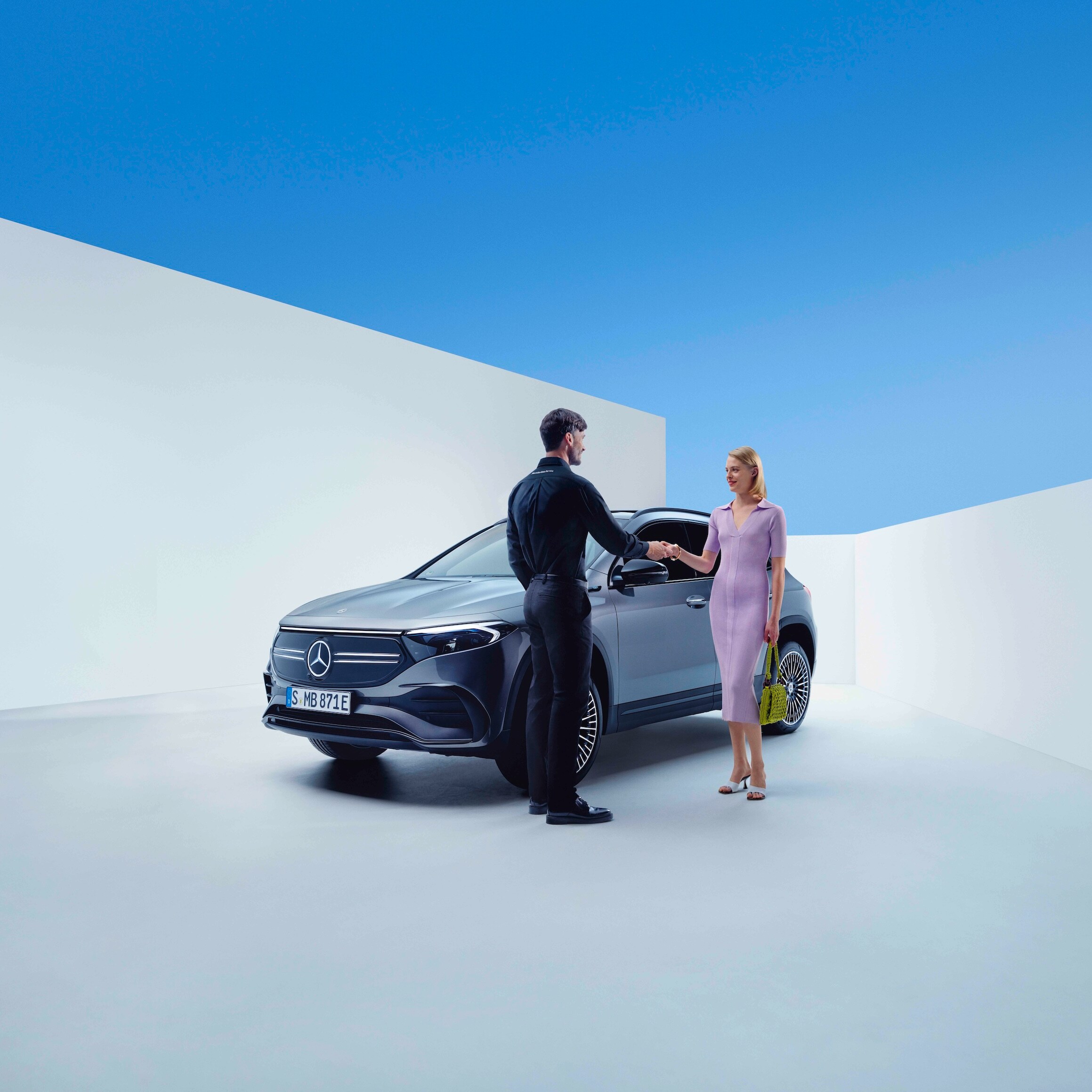 Een Mercedes-Benz medewerker en een vrouw geven elkaar de hand vóór een Mercedes-Benz