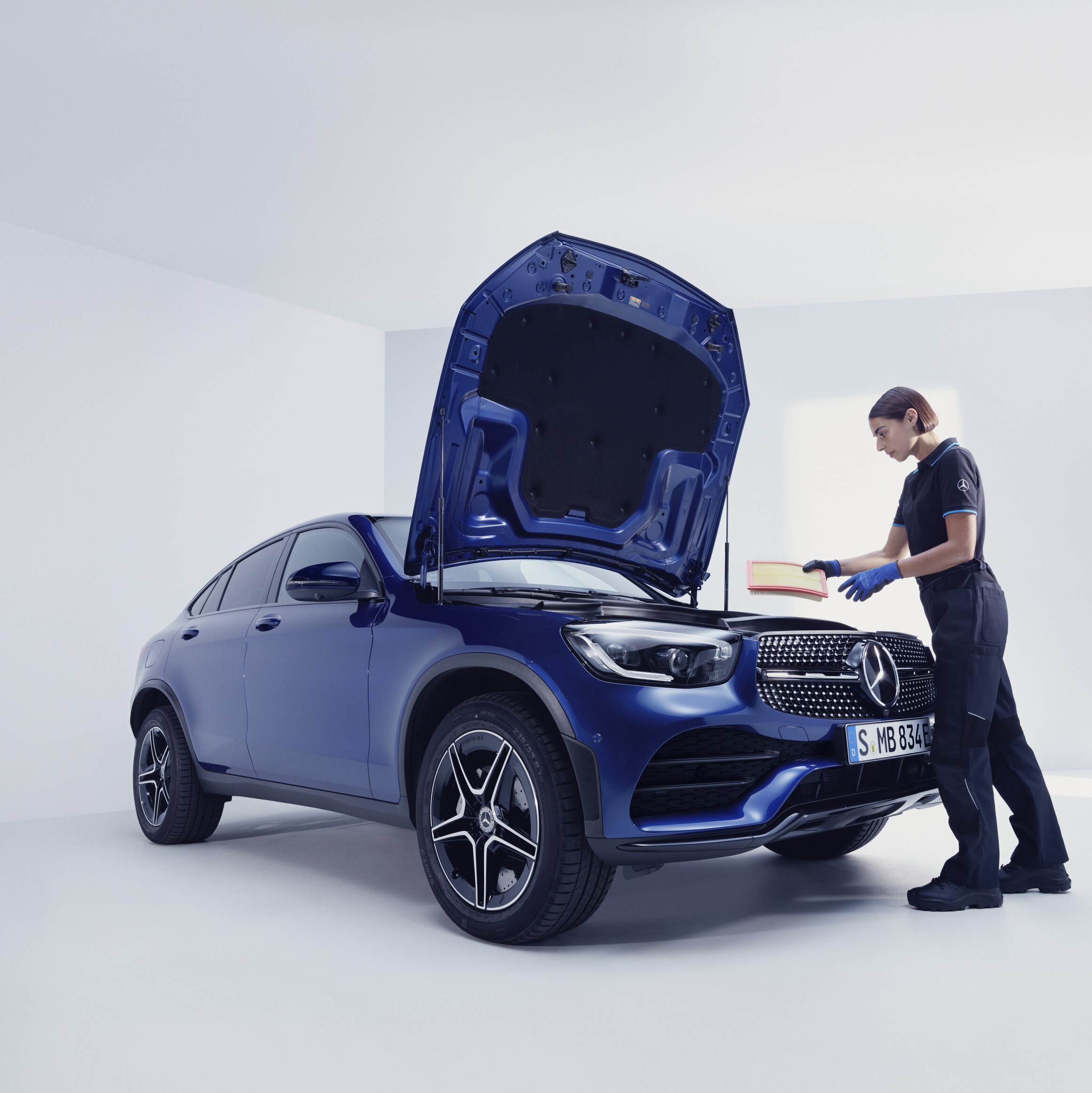 Een Mercedes-Benz technicus en een man staan voor de geopende motorkap van een Mercedes-Benz.