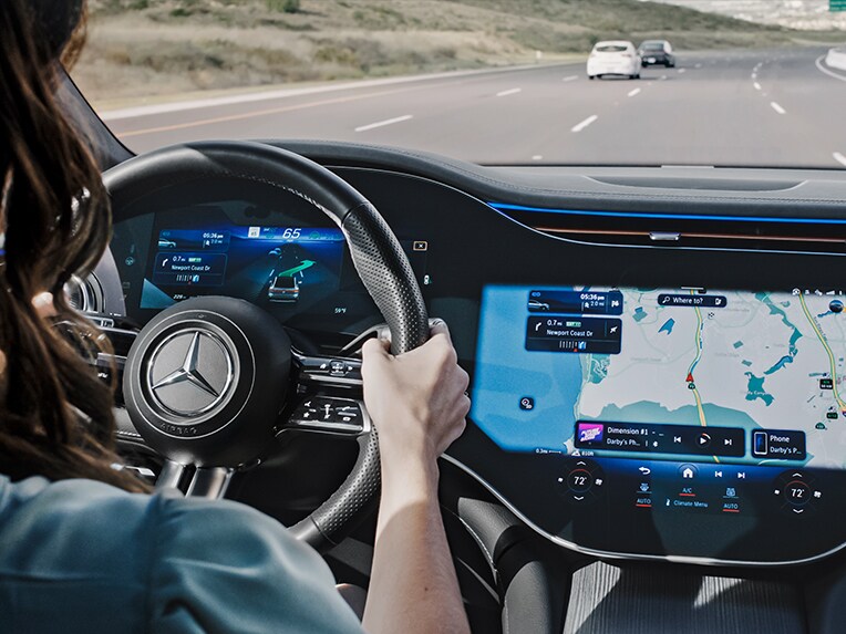Een persoon rijdt op de snelweg en laat zich door het MBUX navigatiesysteem van Mercedes-Benz naar een parkeerplaats navigeren.