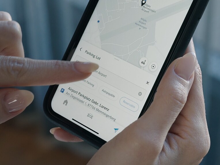 Een persoon tikt op een smartphone. Via off-street parking worden de prijzen van de parkeerplaats weergegeven.