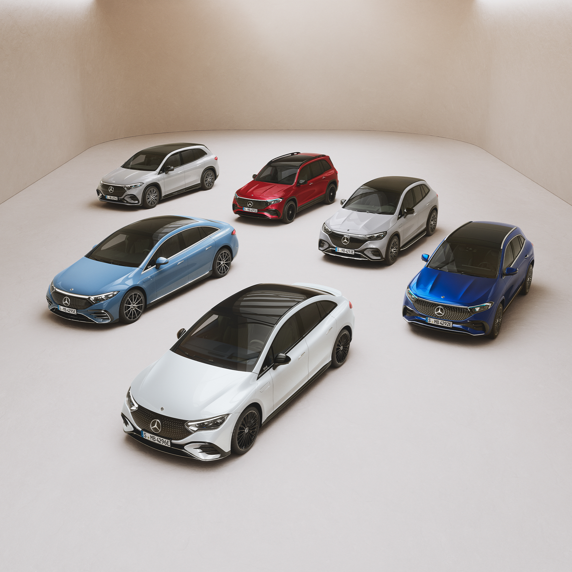 De EQ Range modellen van Mercedes-Benz. De modellen van de EQS Limousine, EQE Limousine, EQA, EQB en EQC staan geparkeerd op een spiegeloppervlak.