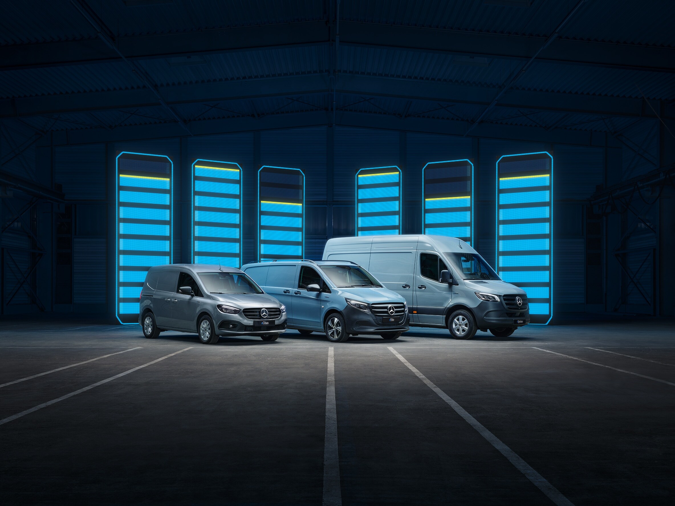 Het assortiment elektrische bestelwagens van Mercedes-Benz wordt tentoongesteld in een futuristisch magazijn met verlichte oplaadpunten