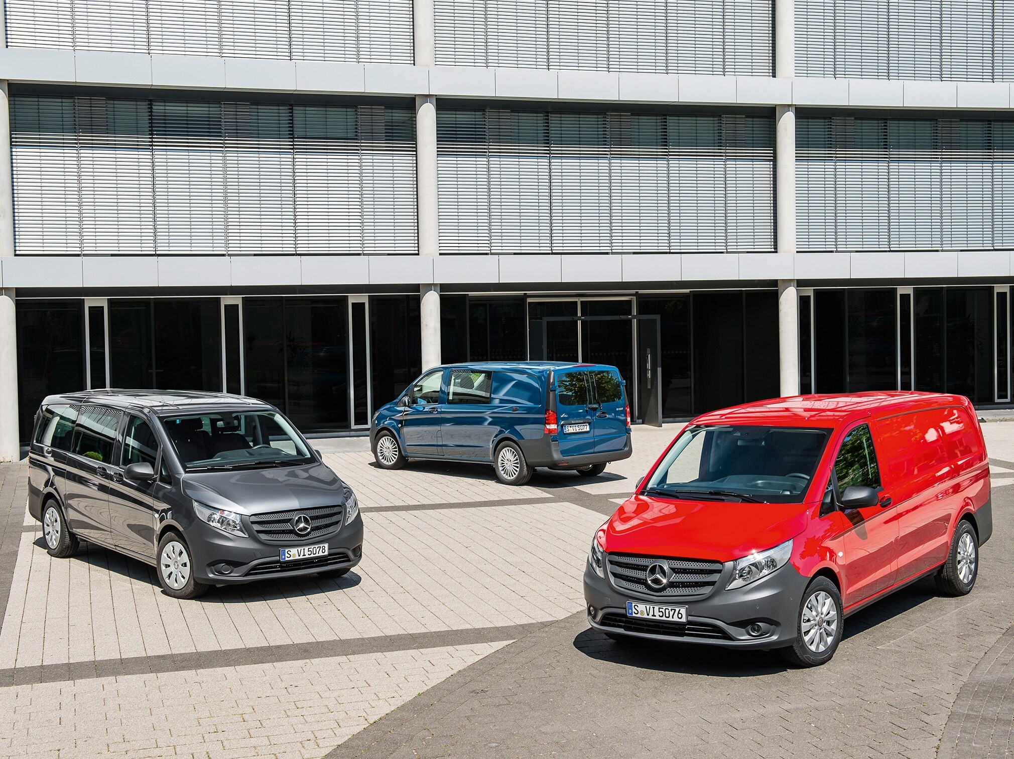 Er staan verschillende Mercedes-Benz Vito’s geparkeerd voor een modern kantoorgebouw