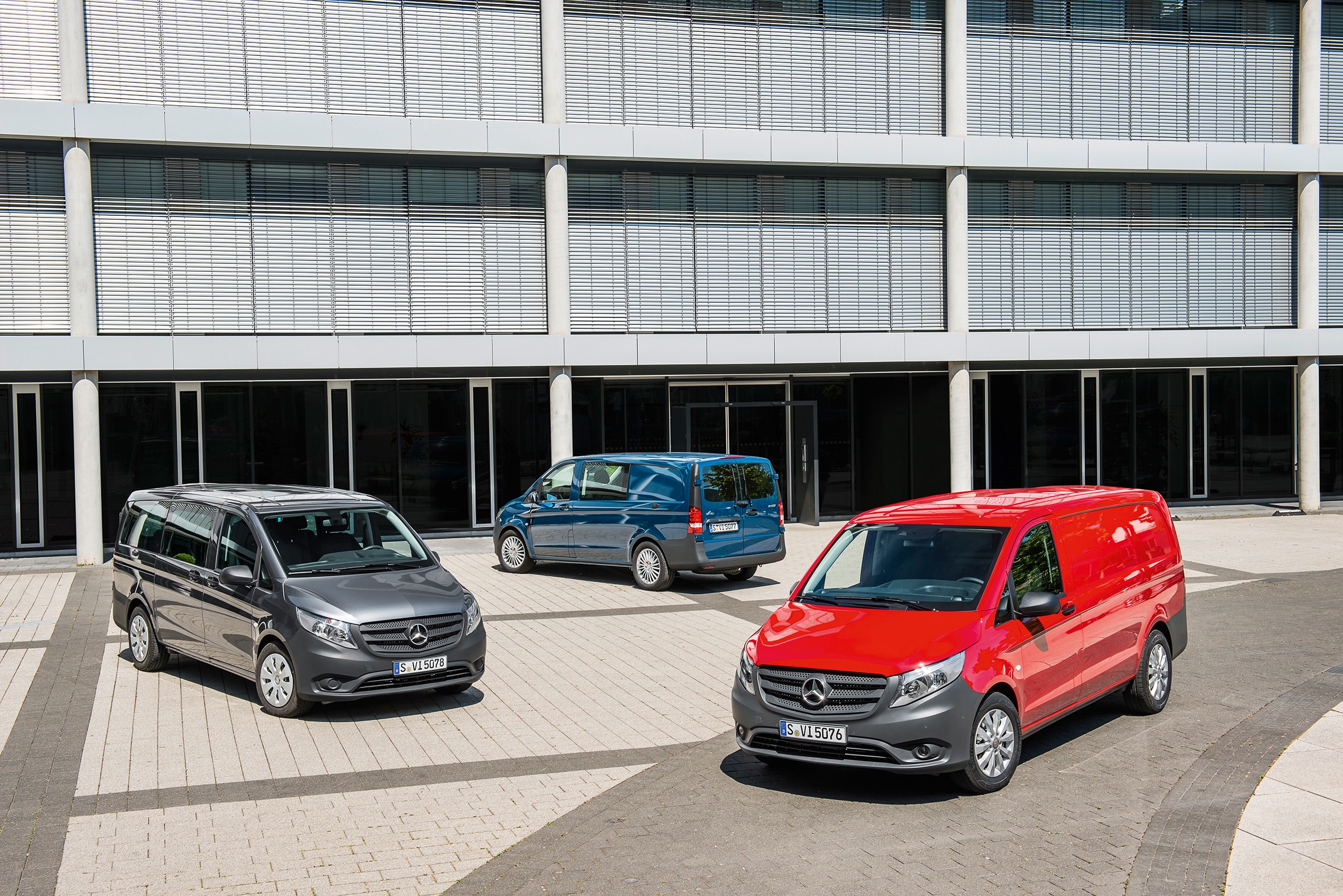 De derde generatie Mercedes-Benz Vito’s | Geschiedenis van bedrijfswagens | Mercedes-Benz Er staan verschillende Mercedes-Benz Vito’s geparkeerd voor een modern kantoorgebouw