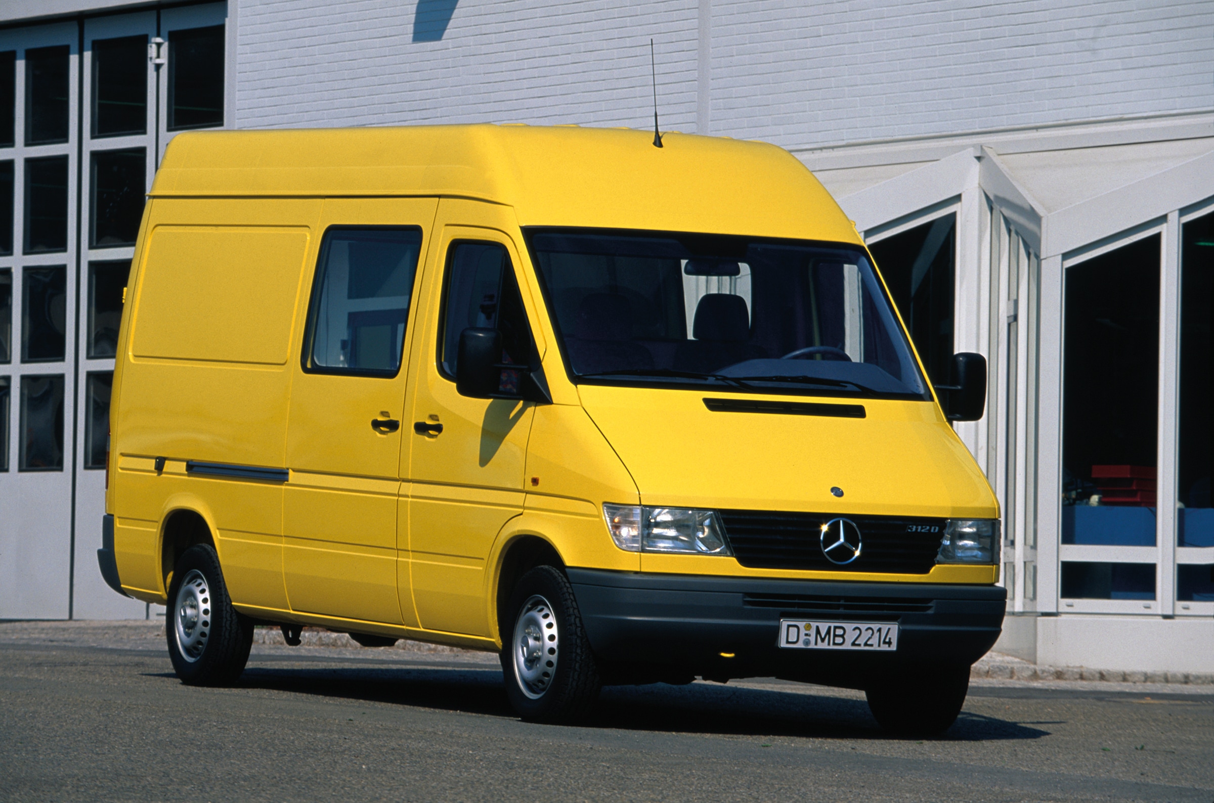De eerste generatie Mercedes-Benz Sprinters | Geschiedenis van bedrijfswagens | Mercedes-Benz Een Sprinter van de eerste generatie staat geparkeerd voor een bedrijfsgebouw