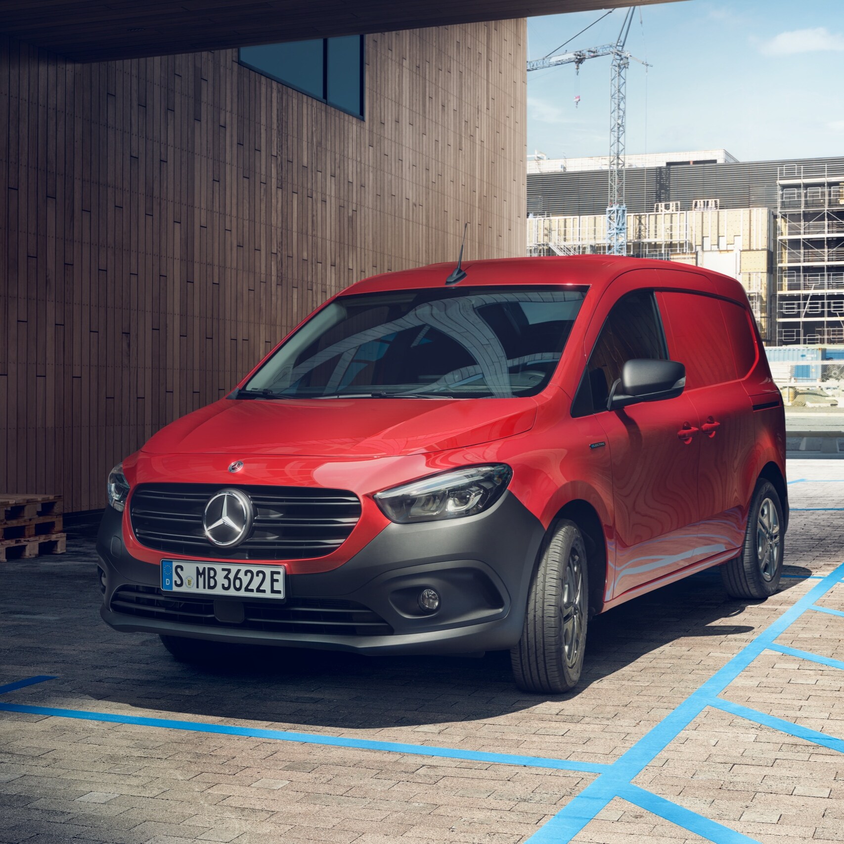De eCitan Gesloten Bestelwagen, een elektrische bestelwagen van Mercedes-Benz, parkeert bij een laadpunt voor een modern gebouw.