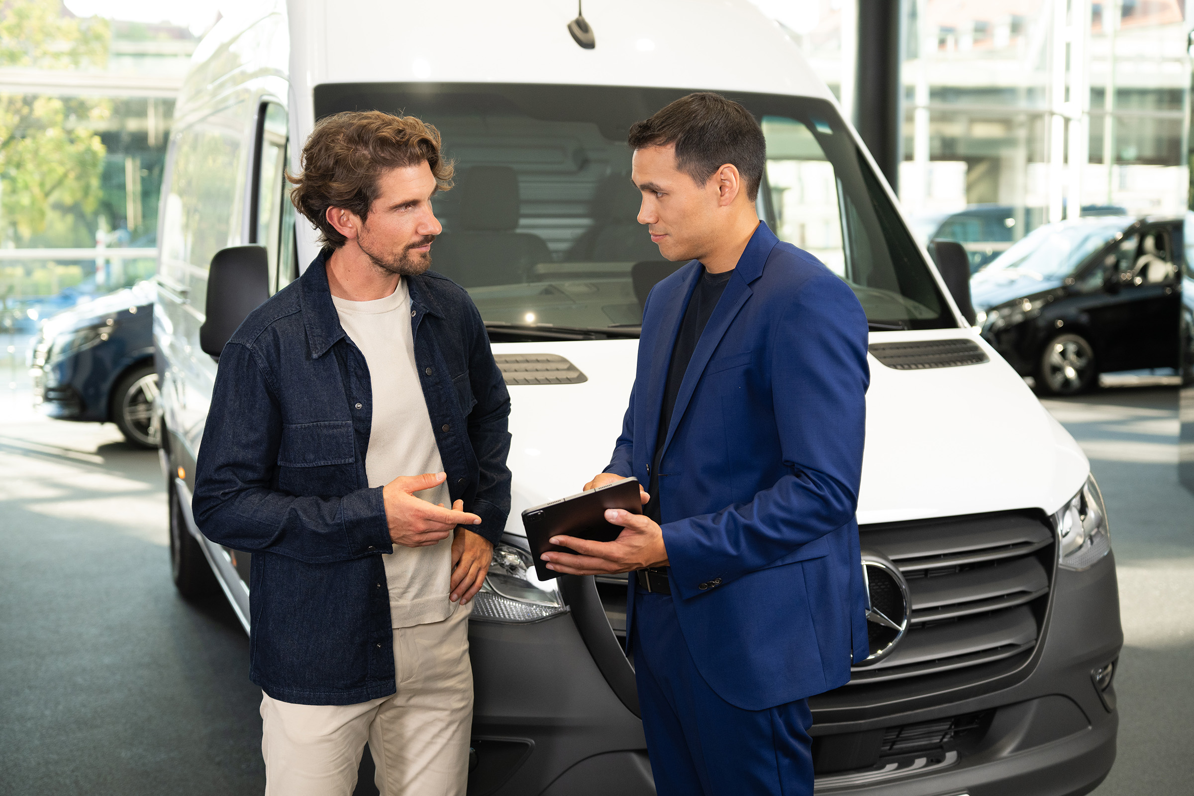 Financieringsleasing | Elektrische modellen | Mercedes-Benz Adviesgesprek over Mercedes-Benz-bedrijfswagens in een showroom, waarbij de nadruk ligt op klantgerichte service.
