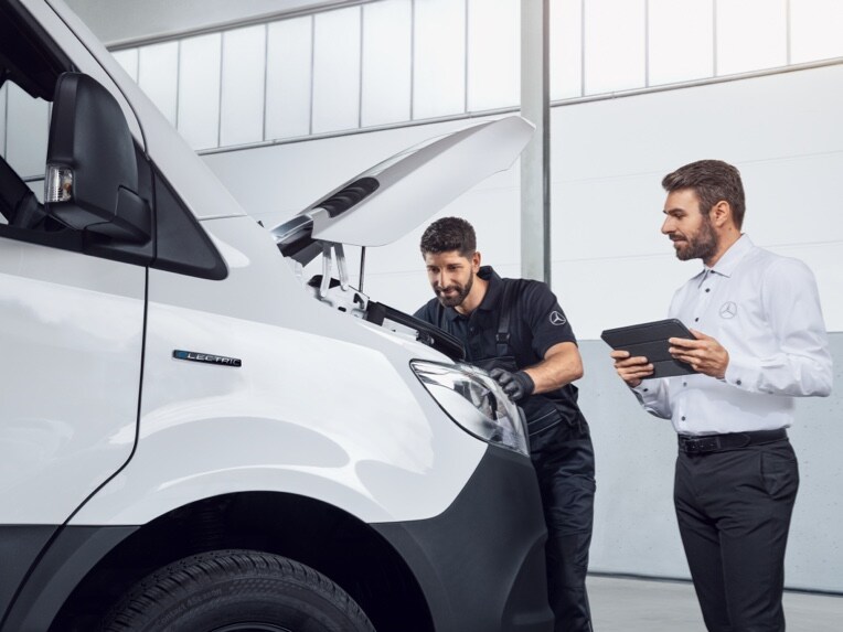 Er wordt onderhoud aan een Mercedes-Benz bestelwagen uitgevoerd.