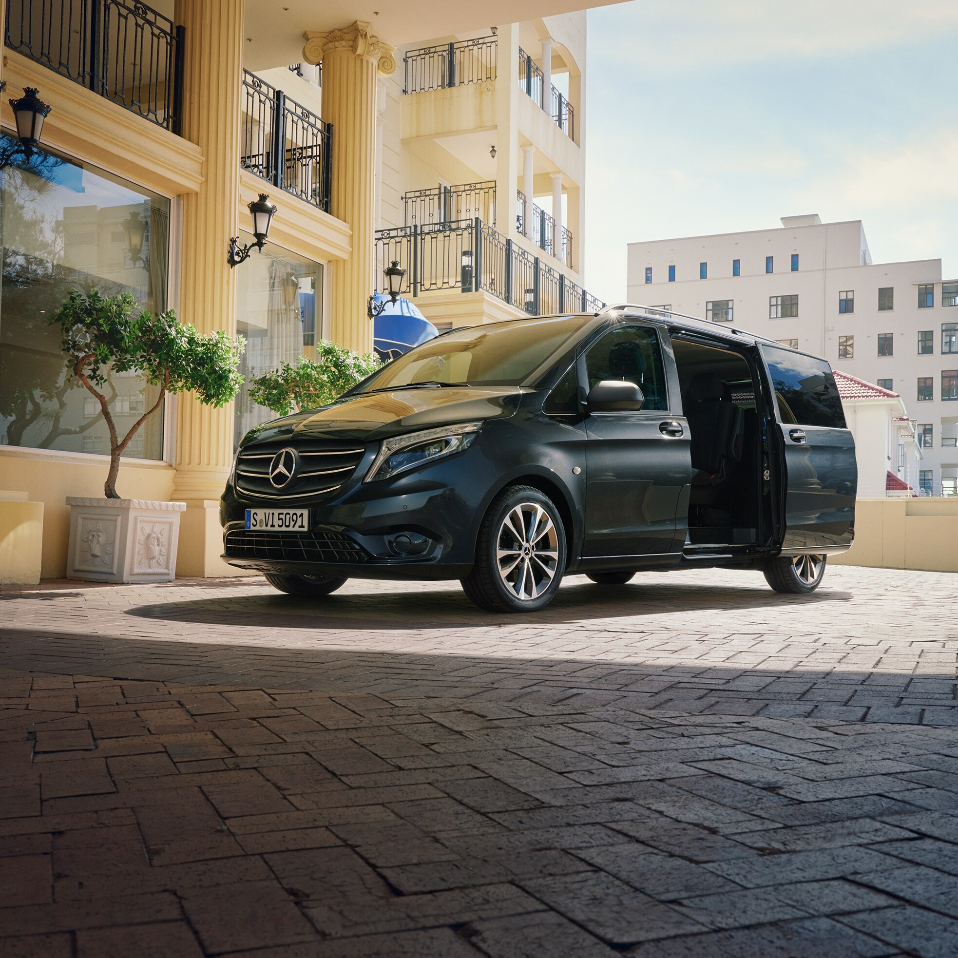 Een Mercedes‑Benz Vito Tourer geparkeerd bij de ingang van een luxe gebouw