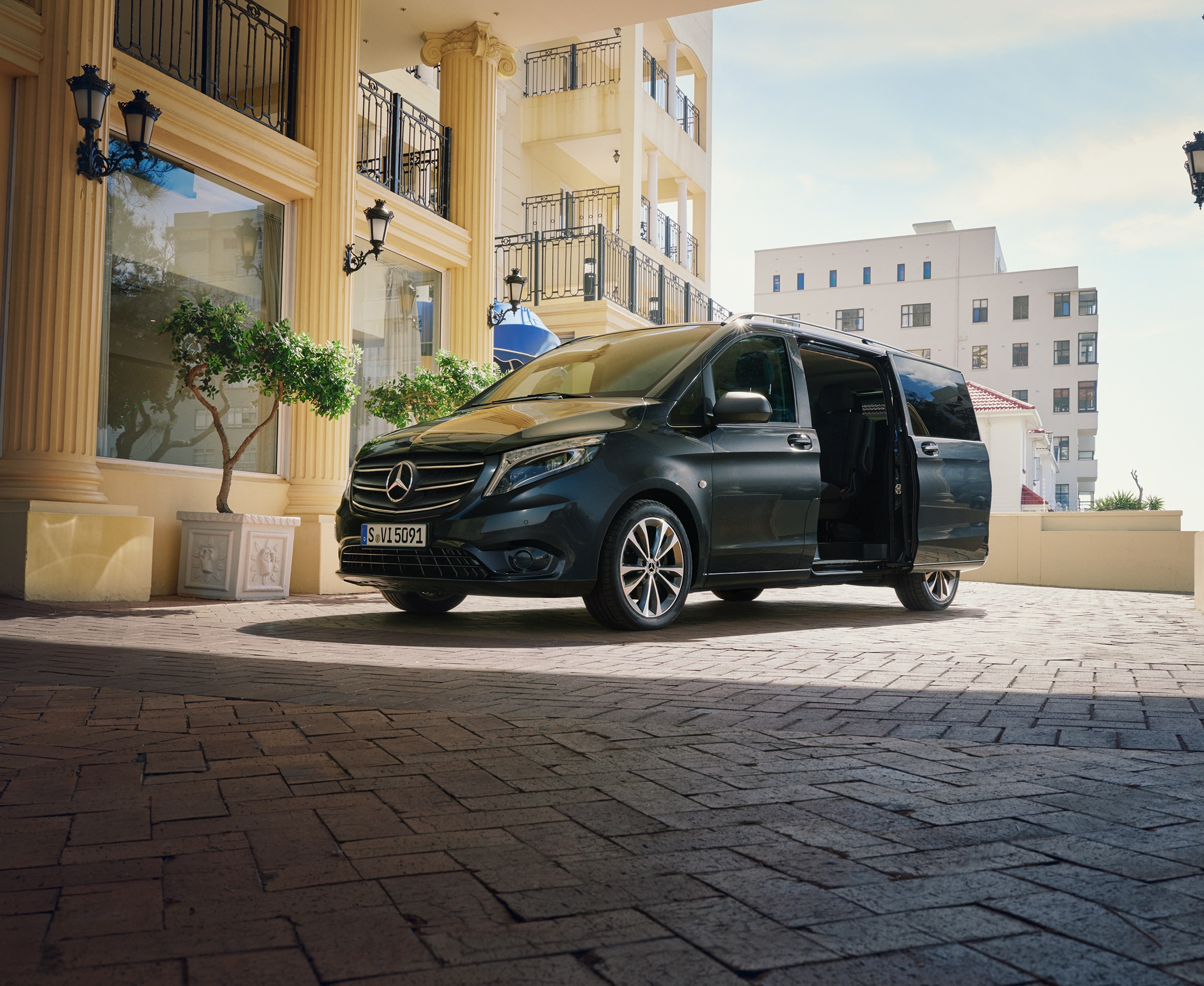 Vito Tourer transport | Alle Vito-modellen | Mercedes-Benz Bestelwagens Een Mercedes‑Benz Vito Tourer geparkeerd bij de ingang van een luxe gebouw