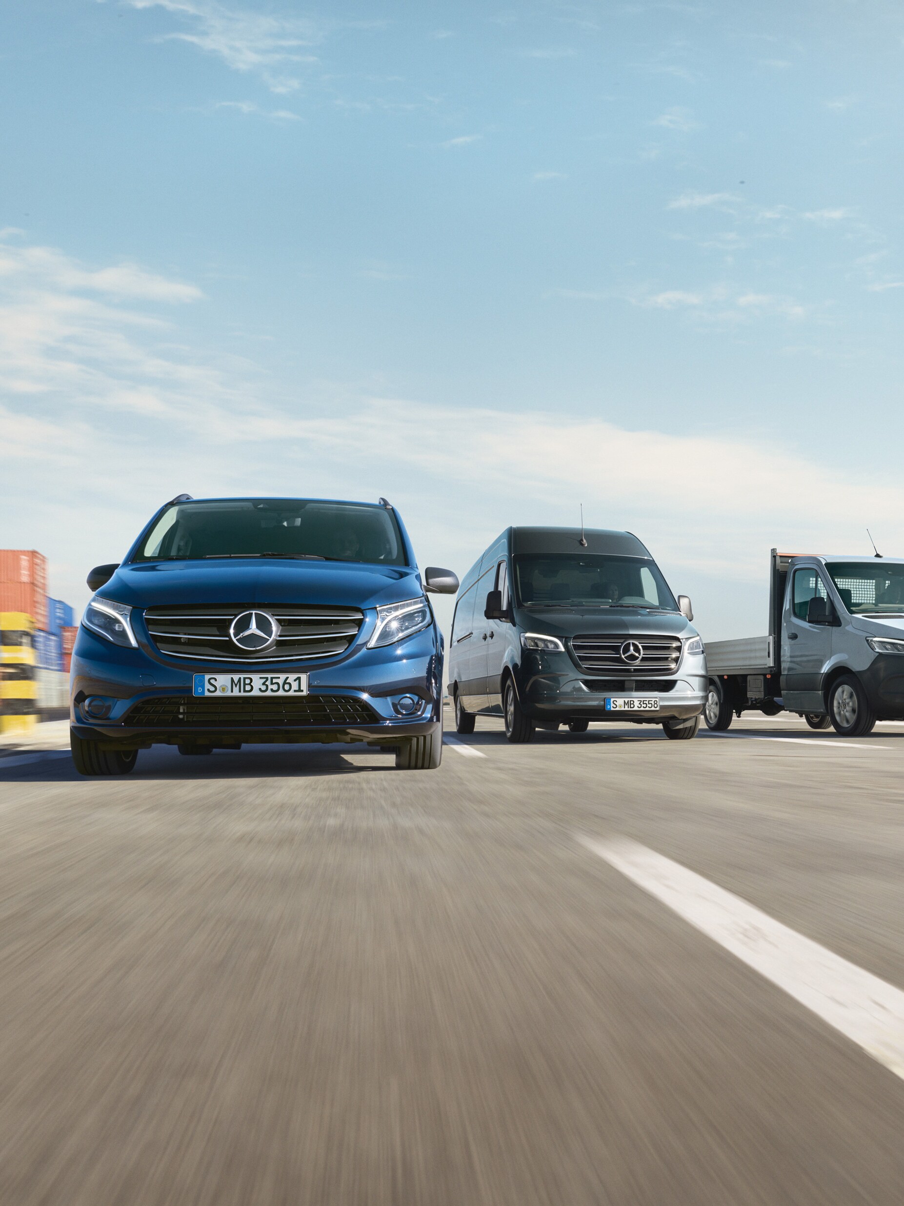Een reeks Mercedes-Benz bestelwagens die naast elkaar geparkeerd staan op een weg naast een laadkade.