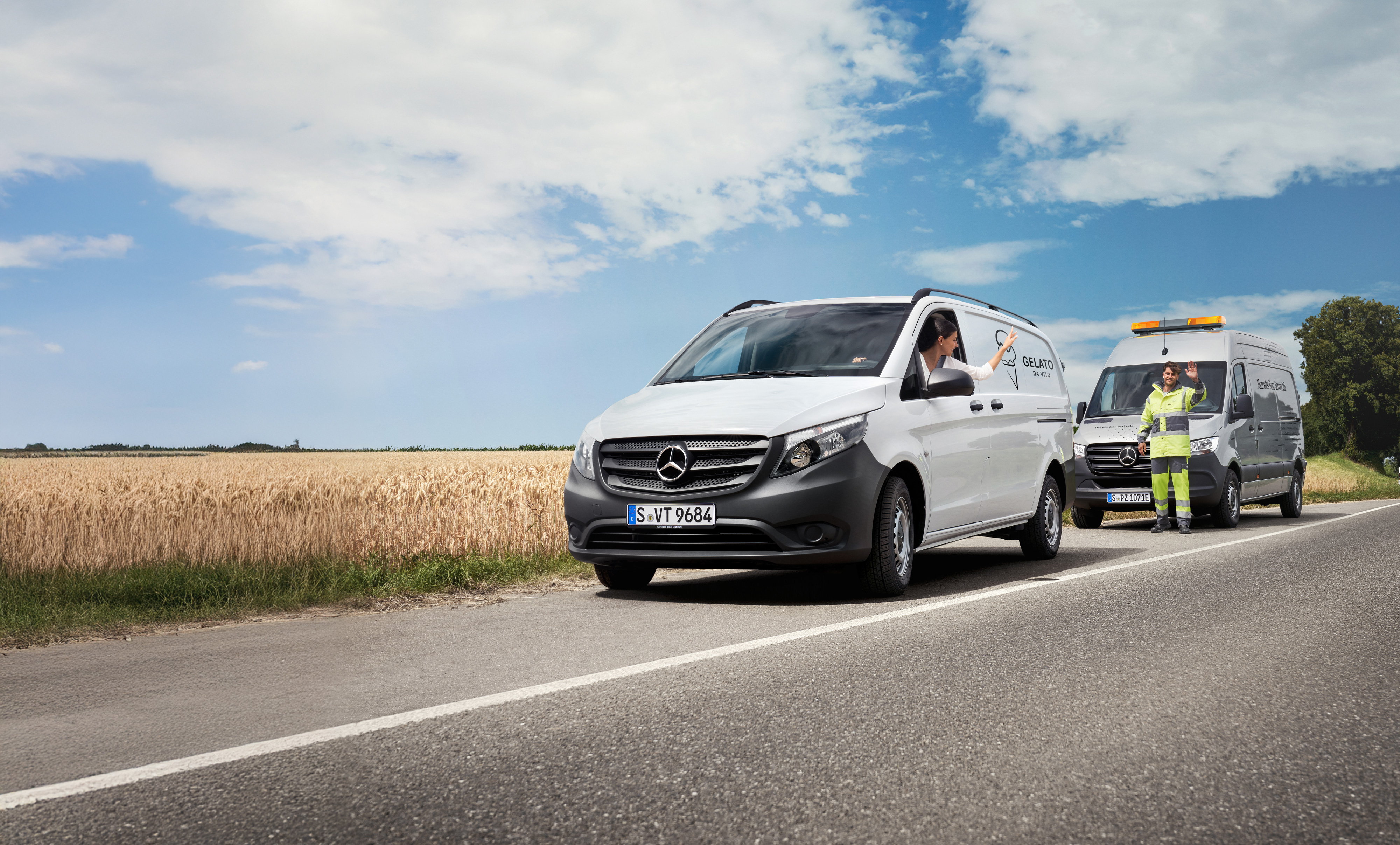 Mercedes-Benz Bedrijfswagen | Vans Care Deskundige ondersteuning onderweg: Mercedes-Benz Service helpt een Bedrijfswagenchauffeur langs de weg, beiden zwaaien vriendelijk.