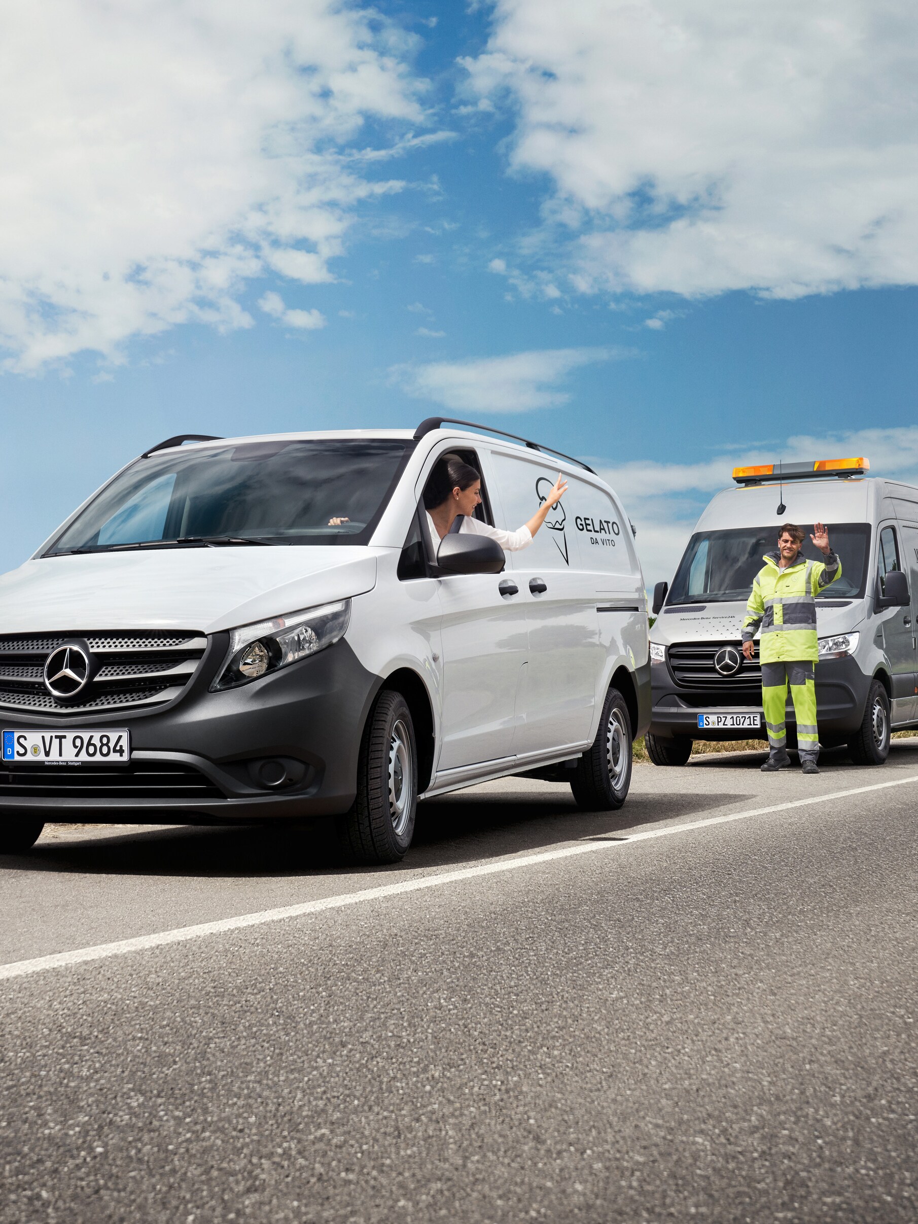 Een vrouw in een witte Mercedes-Benz Vito zwaait naar een Mercedes-Benz servicemonteur langs de kant van de weg.