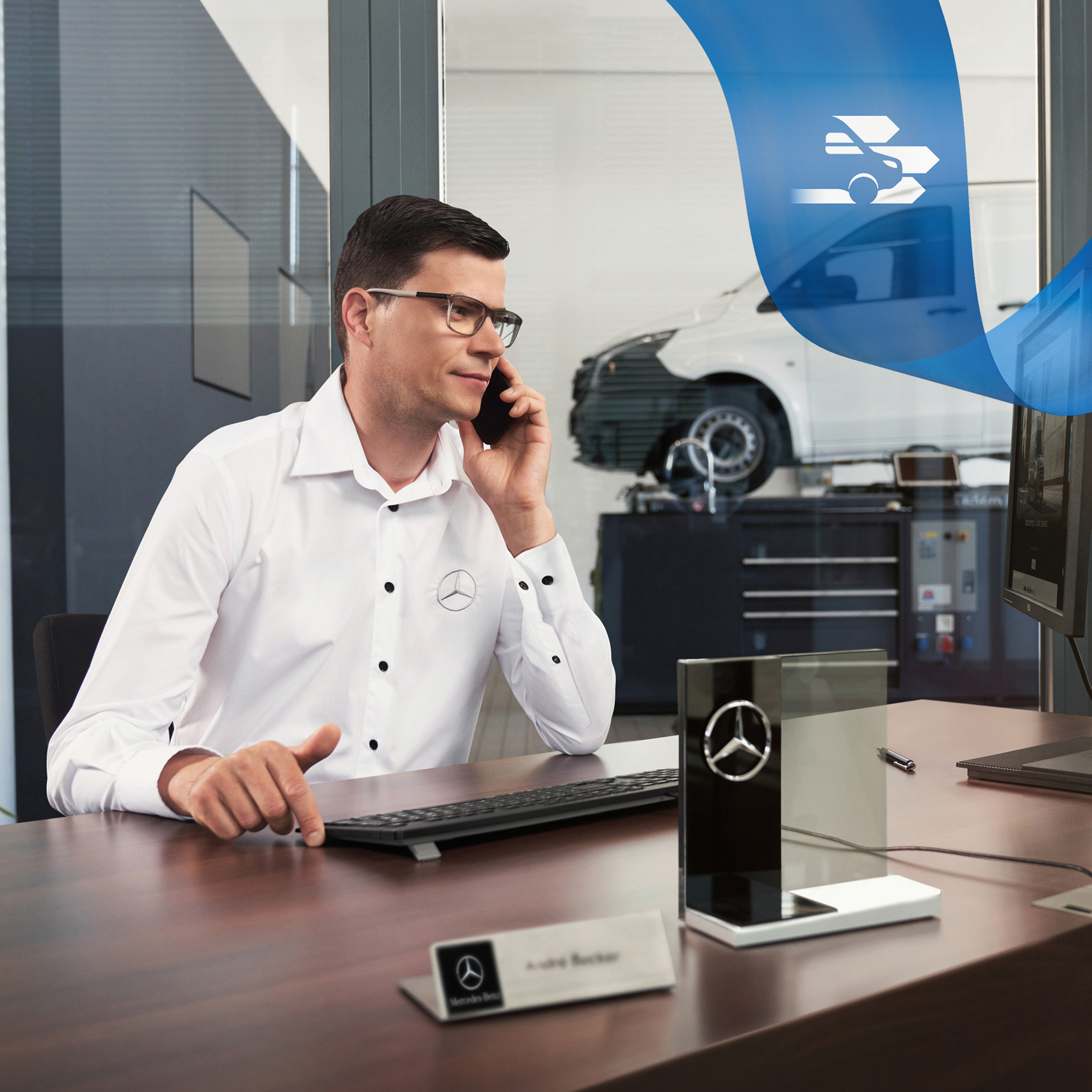 Mercedes-Benz | Vans Care | Hulp bij pech onderweg Mercedes-Benz medewerker telefoneert aan een bureau met een Mercedes-Benz Vito Gesloten Bestelwagen in de werkplaats.