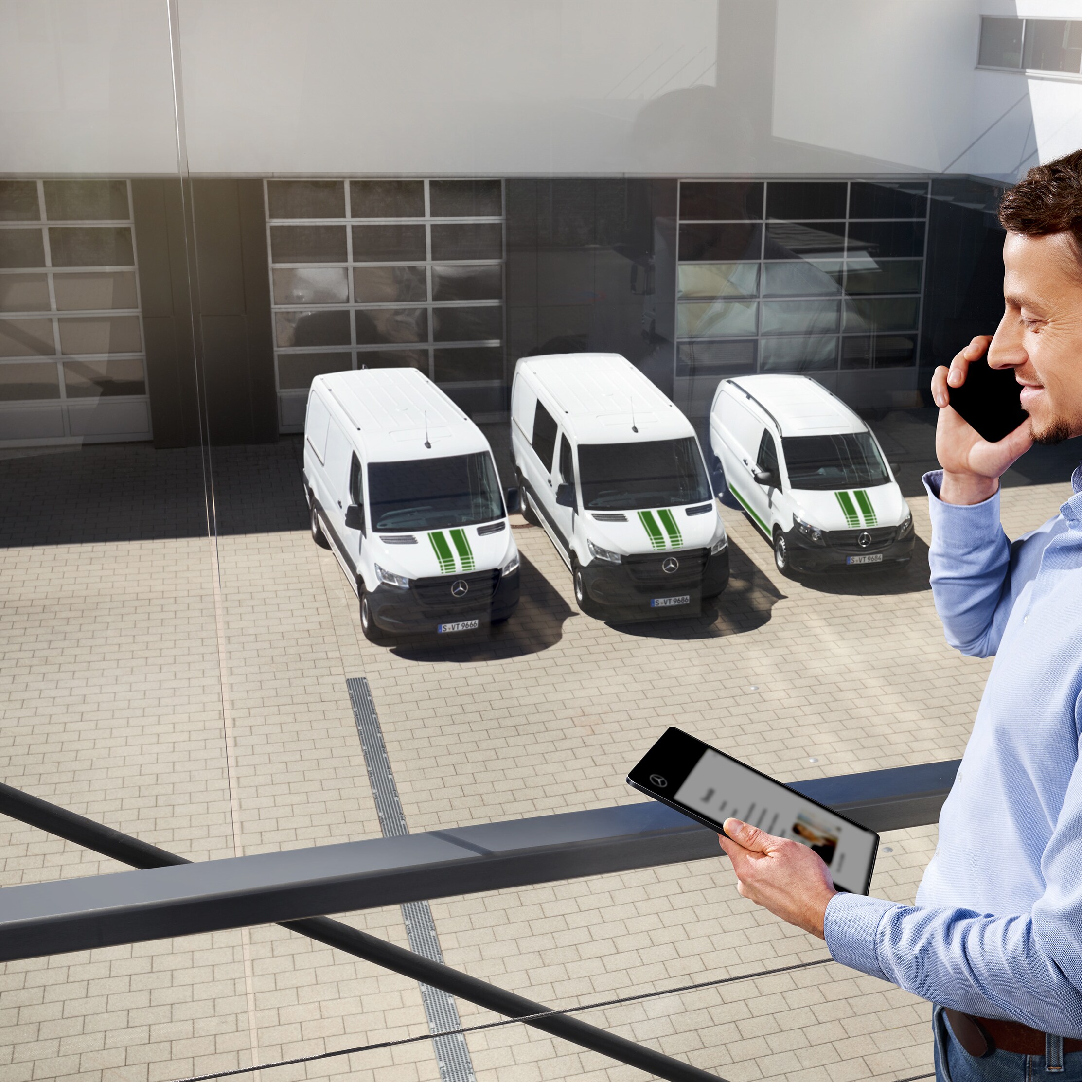 Klant aan de telefoon voor een vloot van witte Mercedes-Benz bestelwagens.