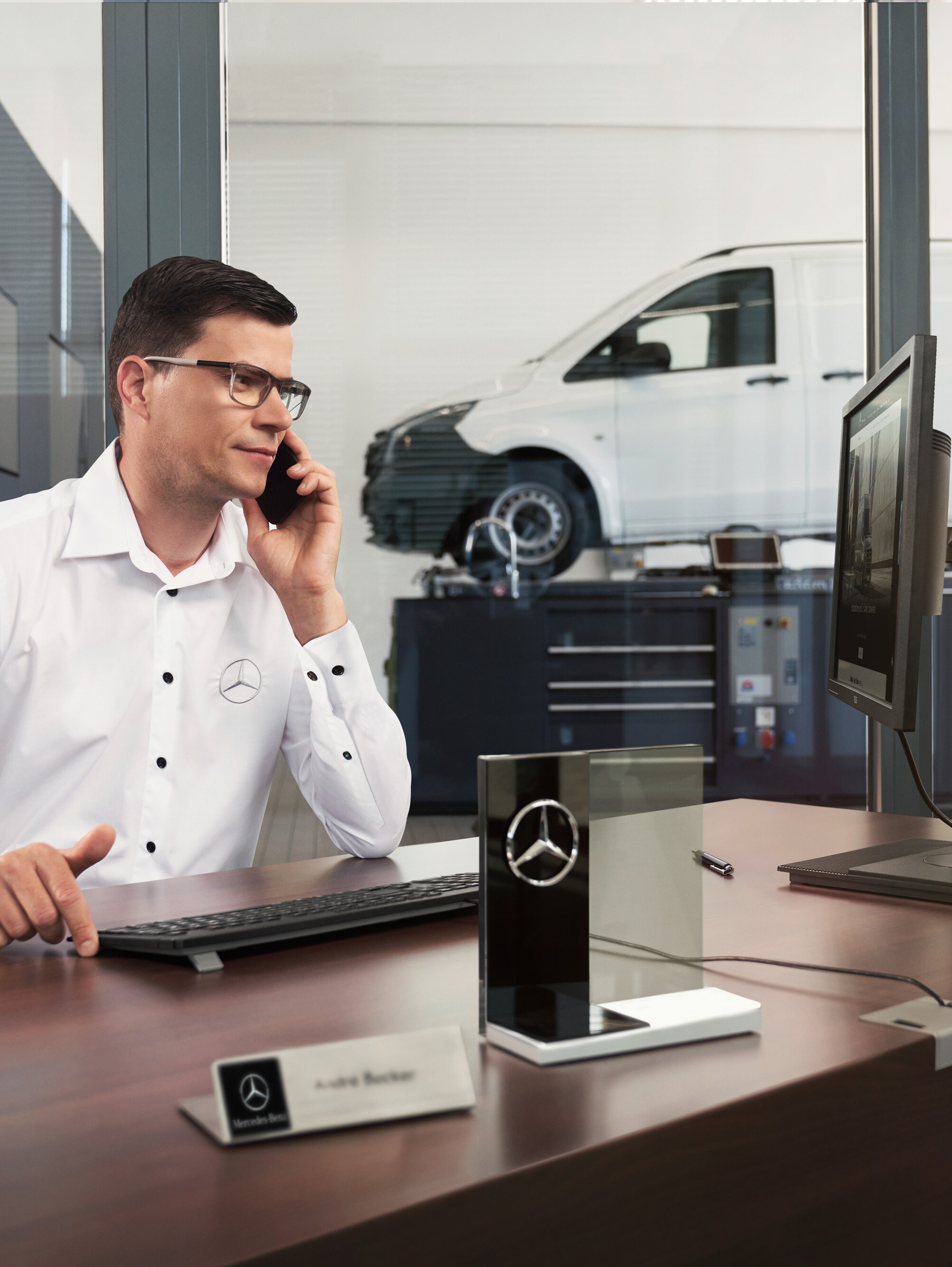 Mercedes-Benz serviceadviseur die in een werkplaats telefoneert.