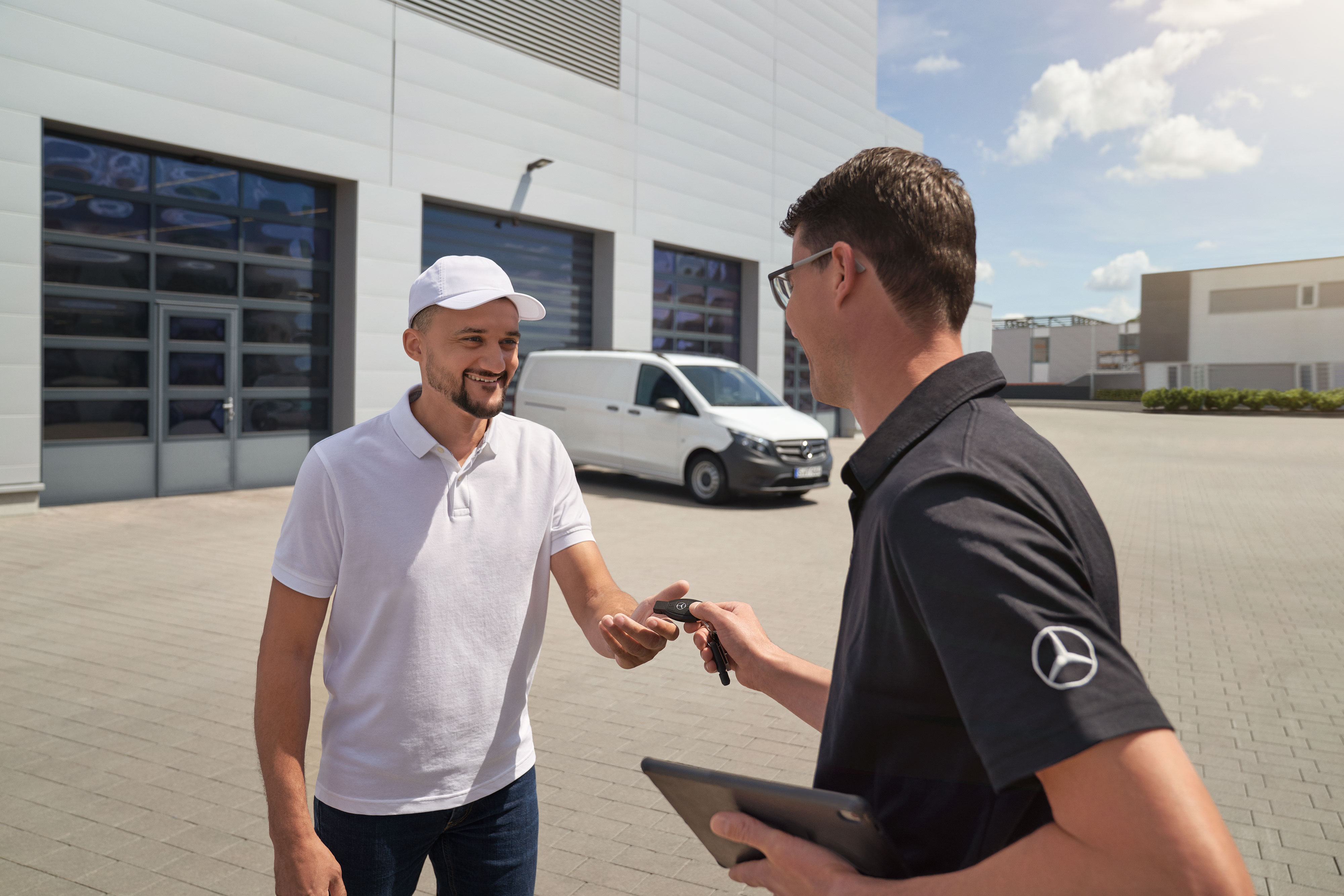 Mercedes-Benz | Comfort | Haal- en brengservice Mercedes-Benz technicus overhandigt sleutels aan een klant met een witte Mercedes-Benz Vito bestelwagen op de achtergrond.