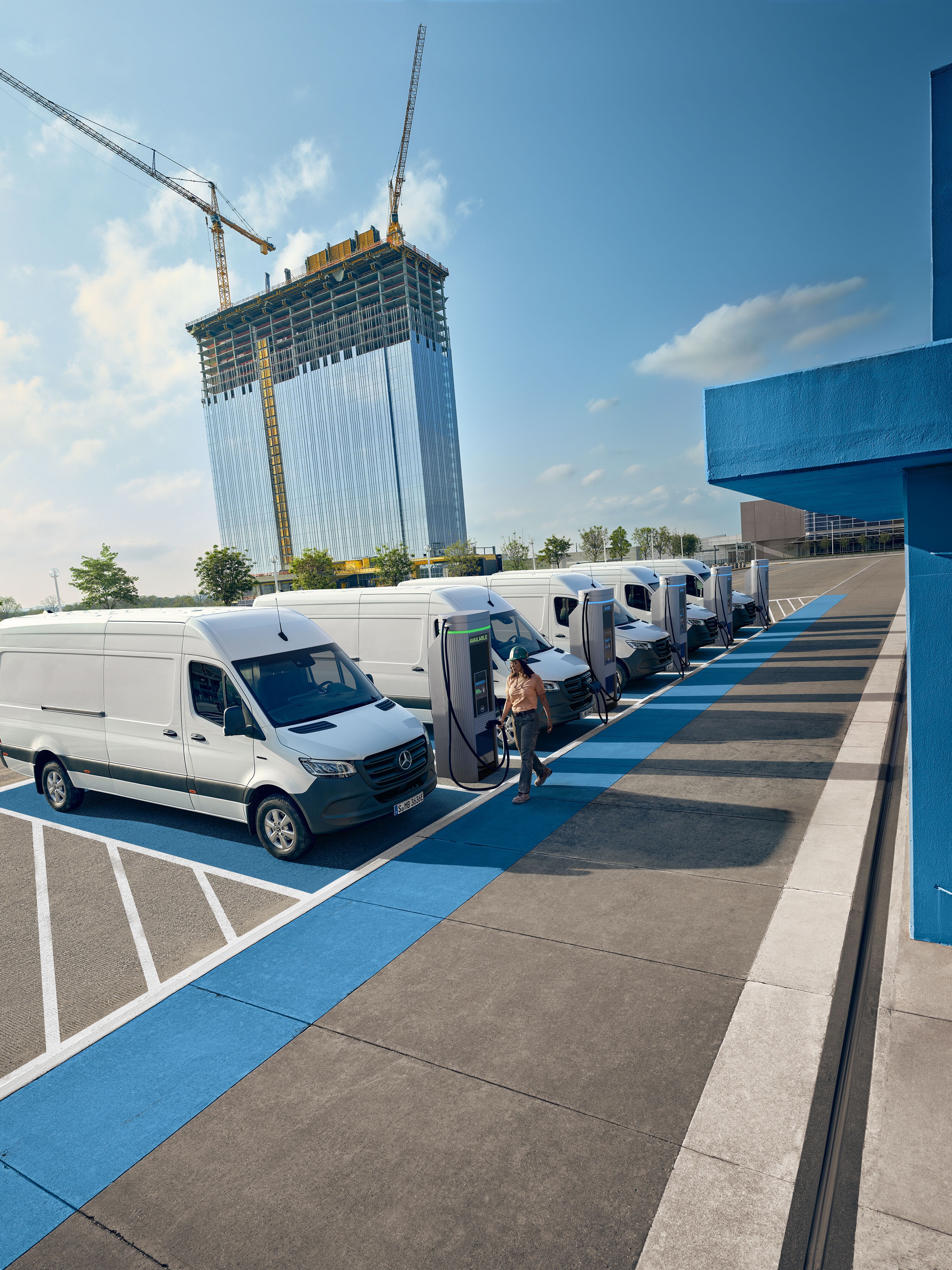 Een vloot witte elektrische Mercedes-Benz bestelwagens geparkeerd bij een laadstation.