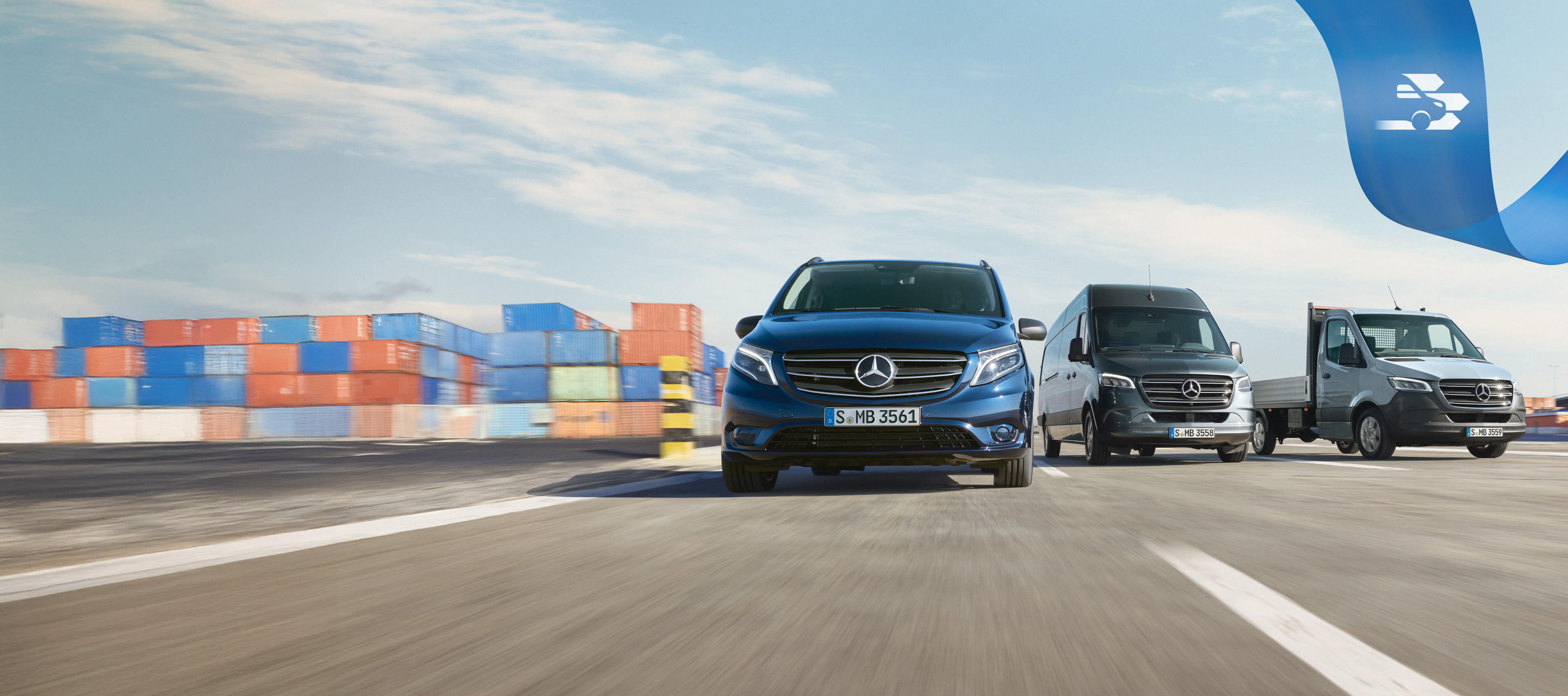 Mercedes Benz Comfort Mobilovan Een reeks Mercedes-Benz bestelwagens op de weg met zeecontainers op de achtergrond.
