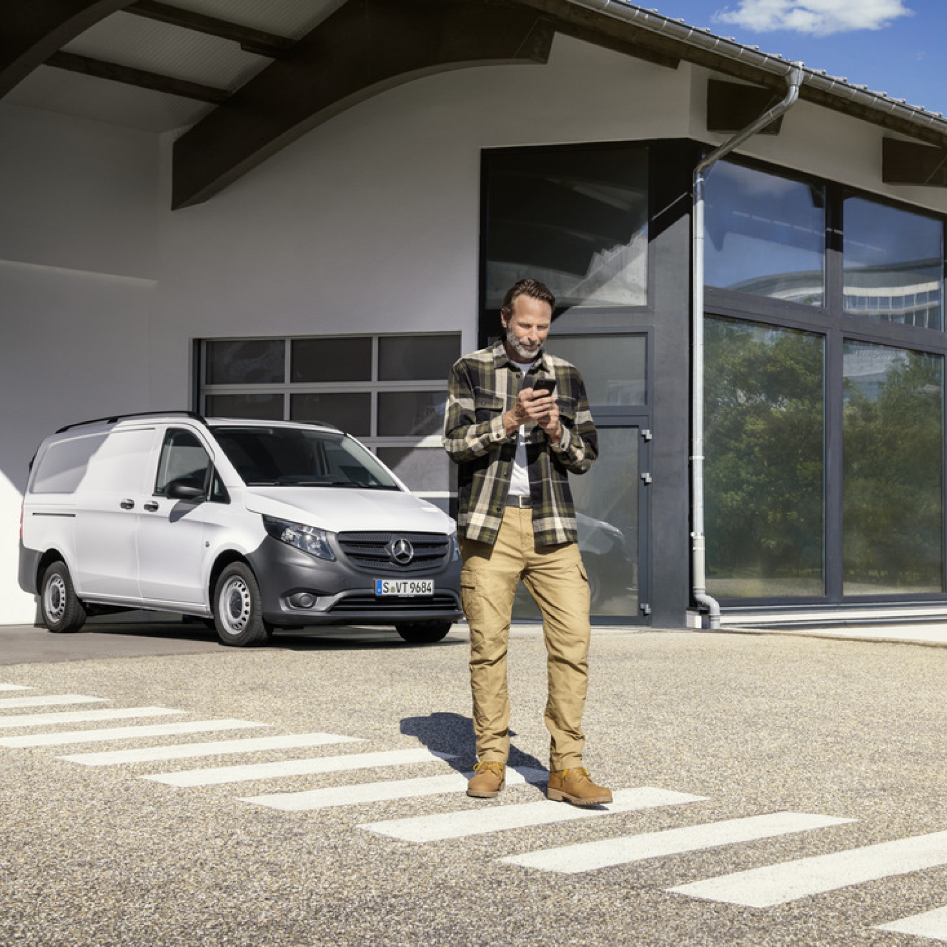 Mercedes-Benz Store | Digitaal extra | Mercedes-Benz Een persoon met een smartphone voor een Mercedes-Benz Vito.
