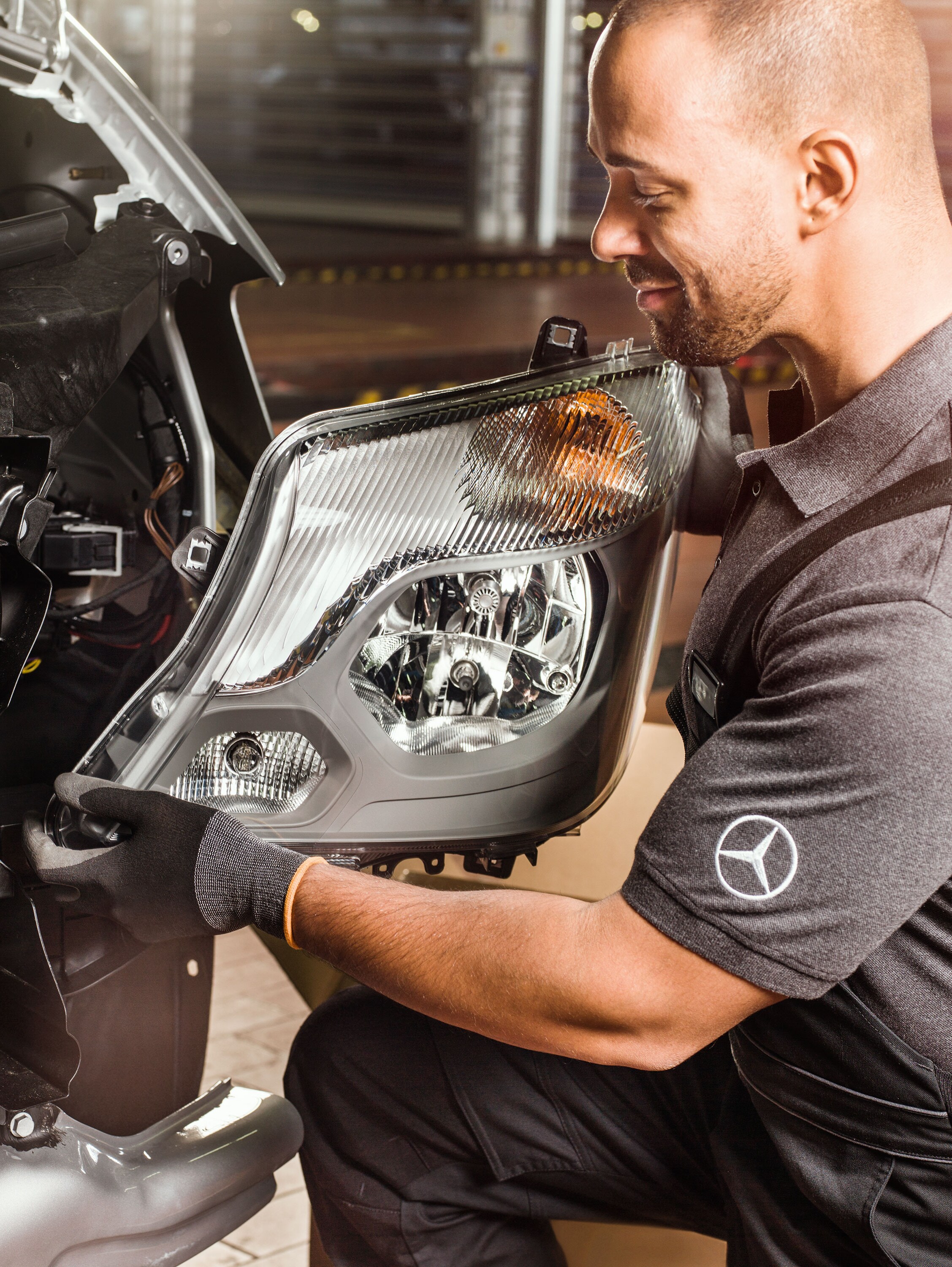 Monteur controleert Mercedes-Benz originele onderdelen voor een open Sprinter-motor, in overeenstemming met de onderdelencatalogus van Mercedes.