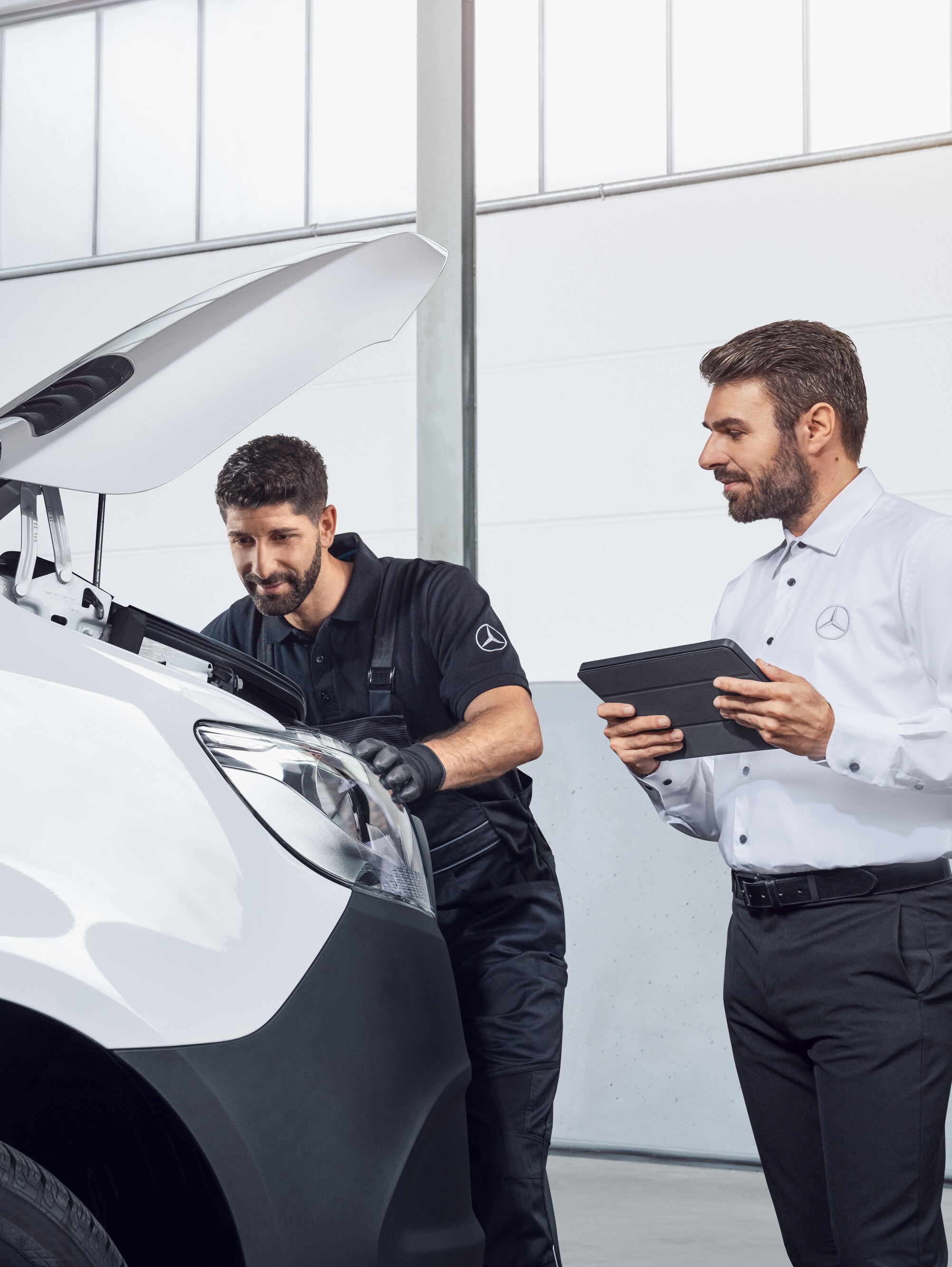 Twee mannen testen een Mercedes Sprinter met tablet en open motorkap, onderwerp: Mercedes-Benz Sprinter onderdelen.