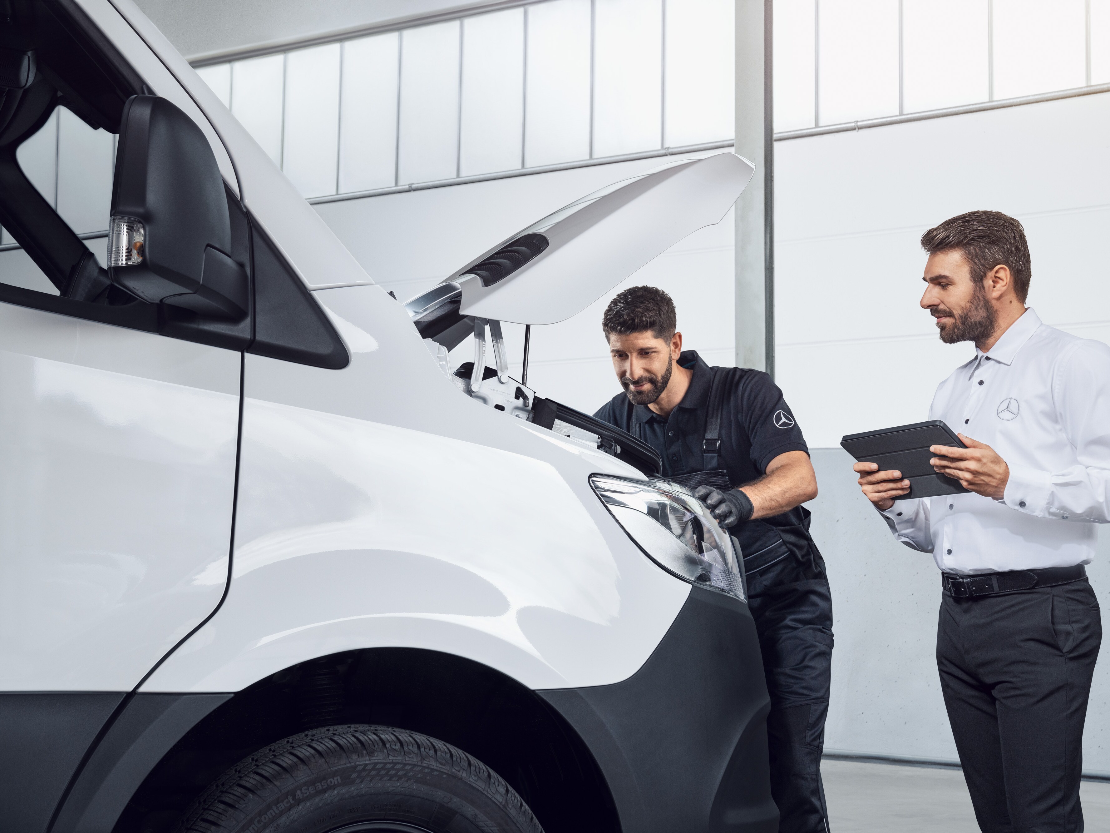 Twee mannen testen een Mercedes Sprinter met tablet en open motorkap, onderwerp: Mercedes-Benz Sprinter onderdelen.
