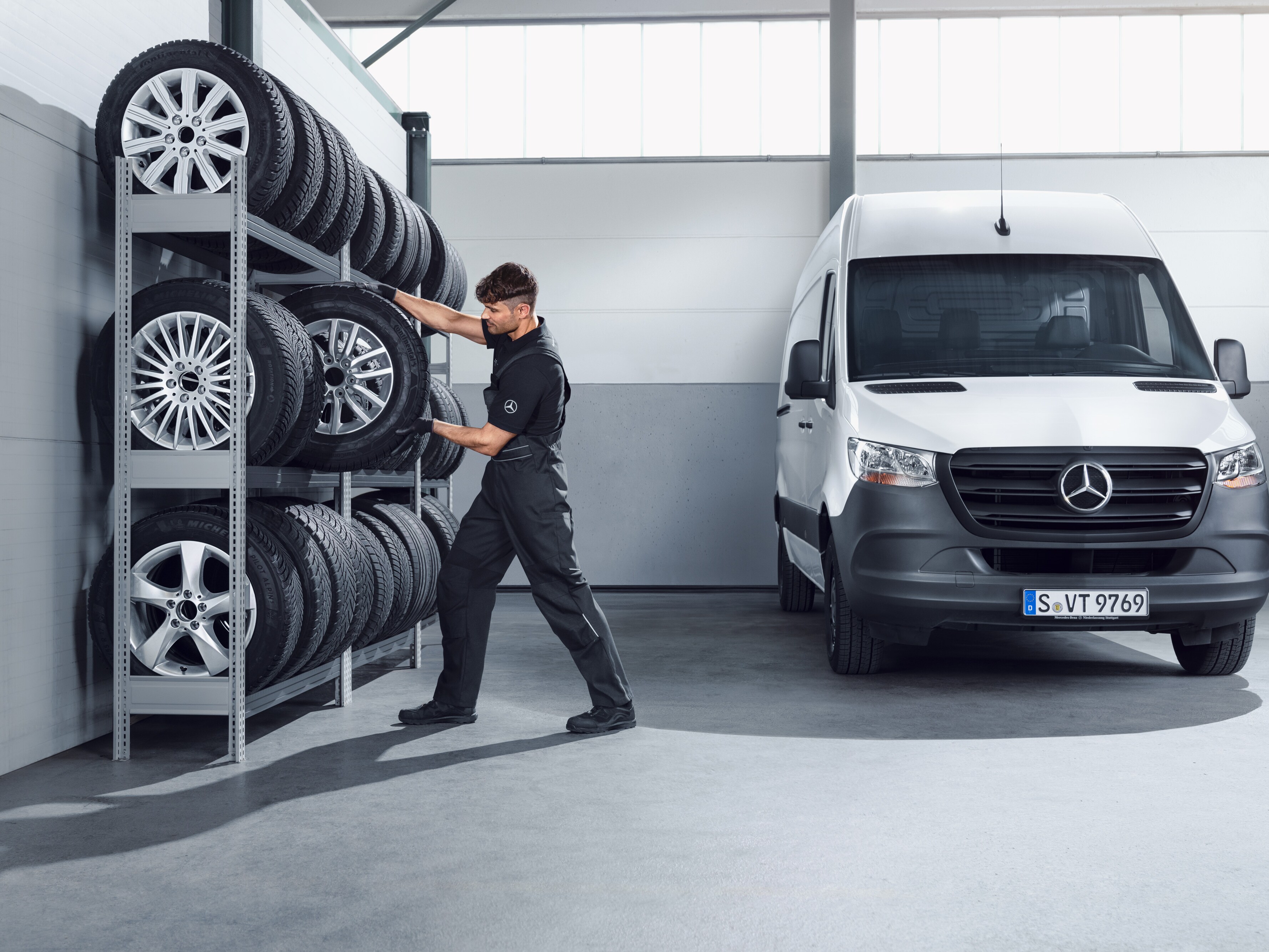 Monteur kiest Mercedes-Benz complete winterwielen voor witte Sprinter uit de werkplaats.