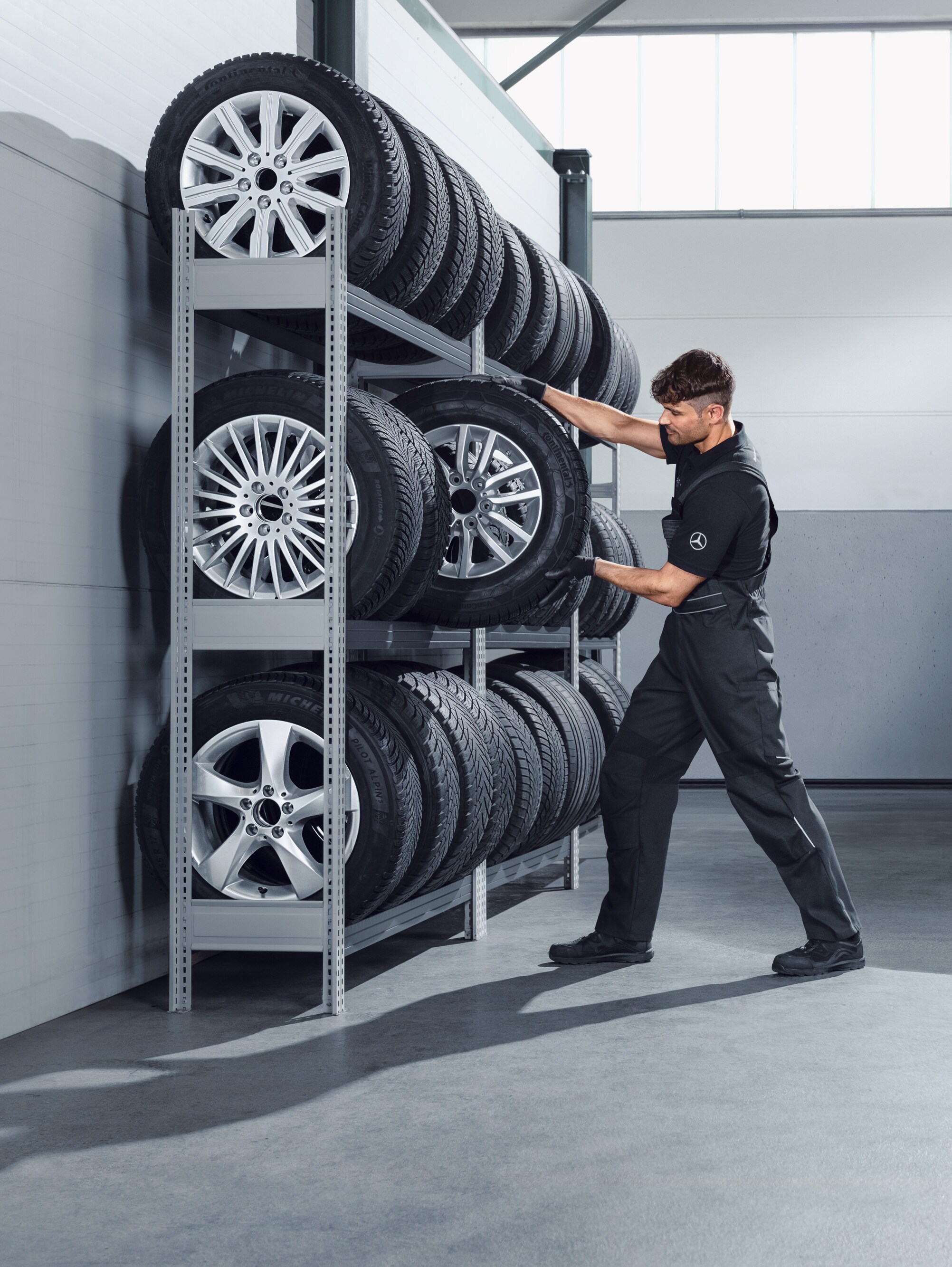 Monteur selecteert Mercedes-Benz complete winterwielen voor een witte Sprinter uit het werkplaatsrek.