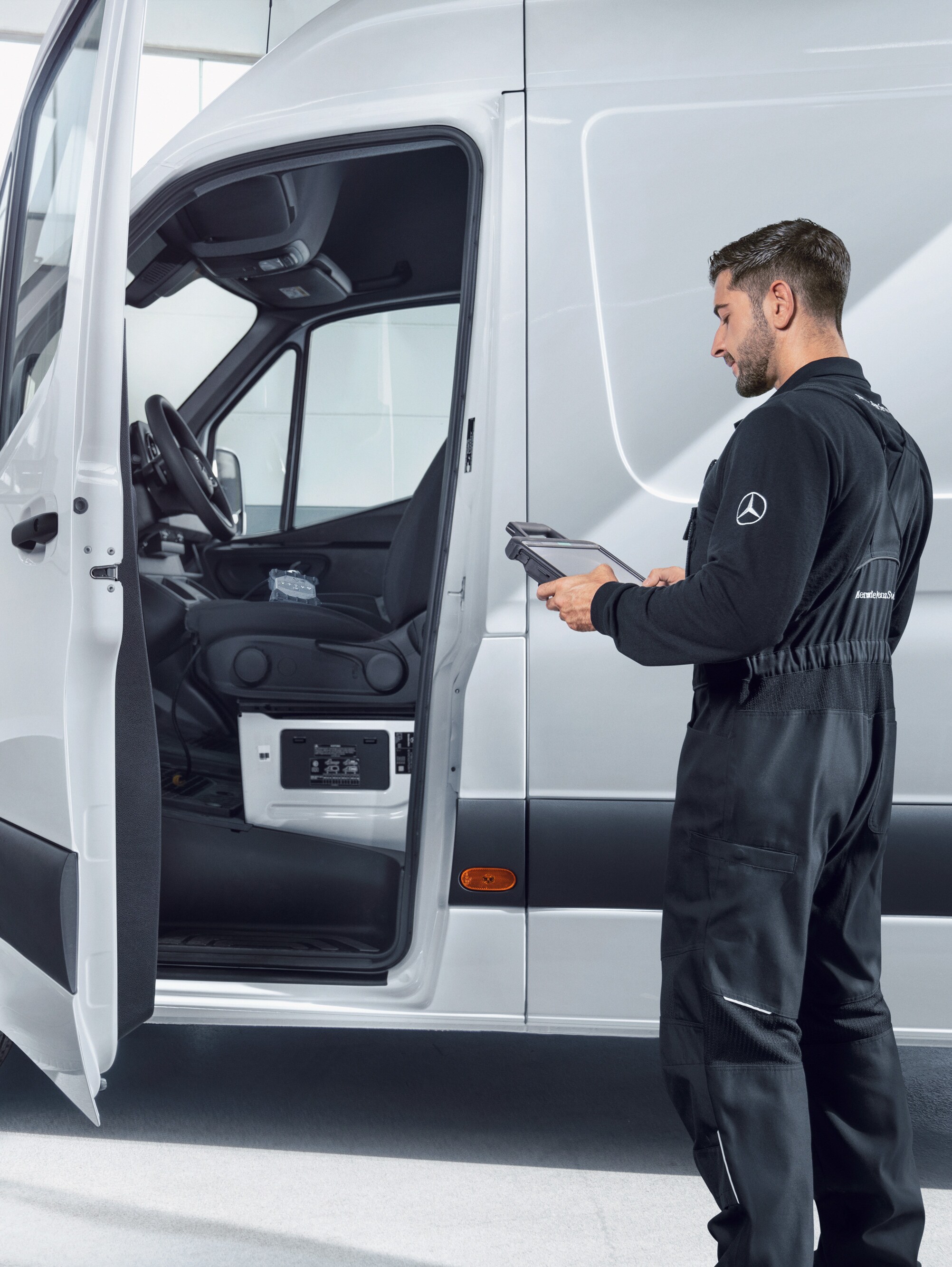 Monteur controleert een witte Mercedes-Benz Bedrijfswagen met een tablet, symbool voor kwaliteitsnormen en de kwaliteitsbelofte.