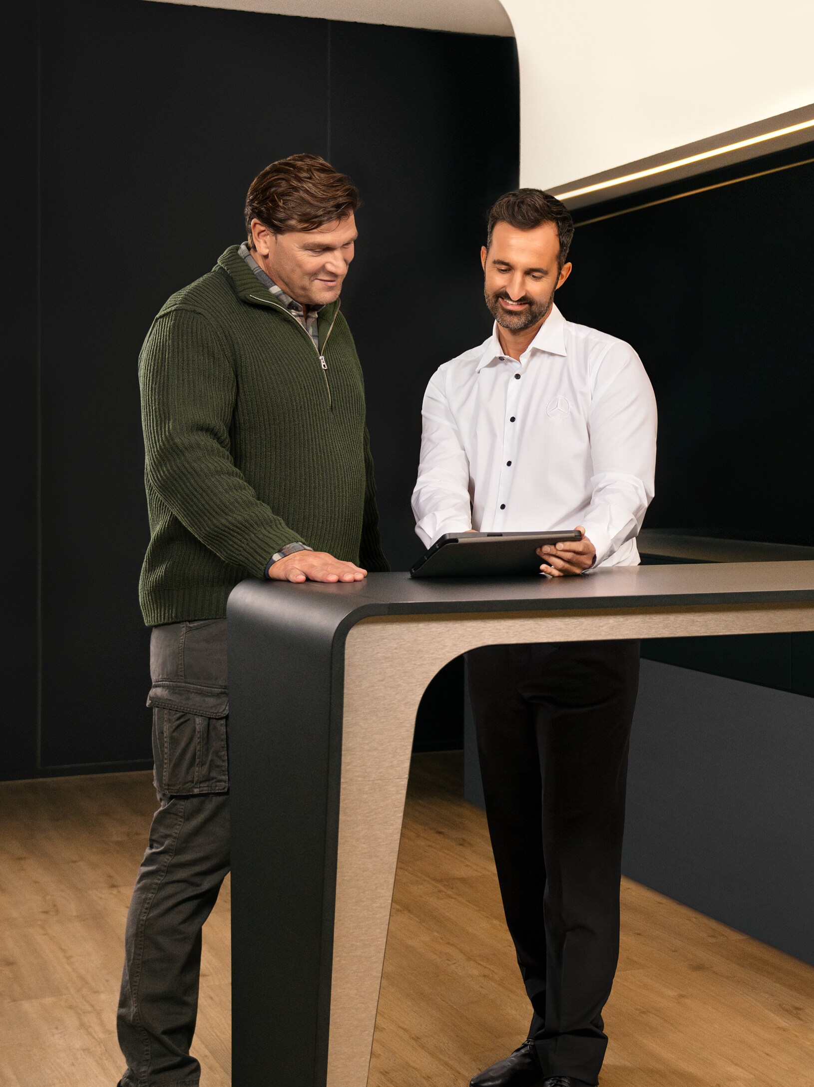 Twee mannen in overleg aan een tafel terwijl ze naar een iPad kijken.