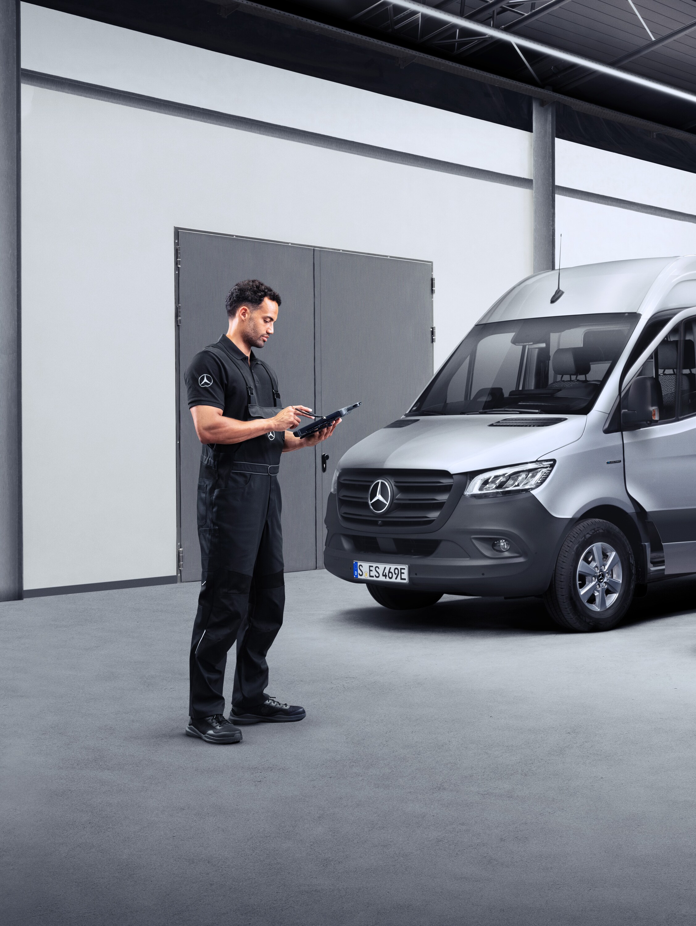 Technicus met tablet voor twee elektrische Mercedes-Benz Bedrijfswagens.
